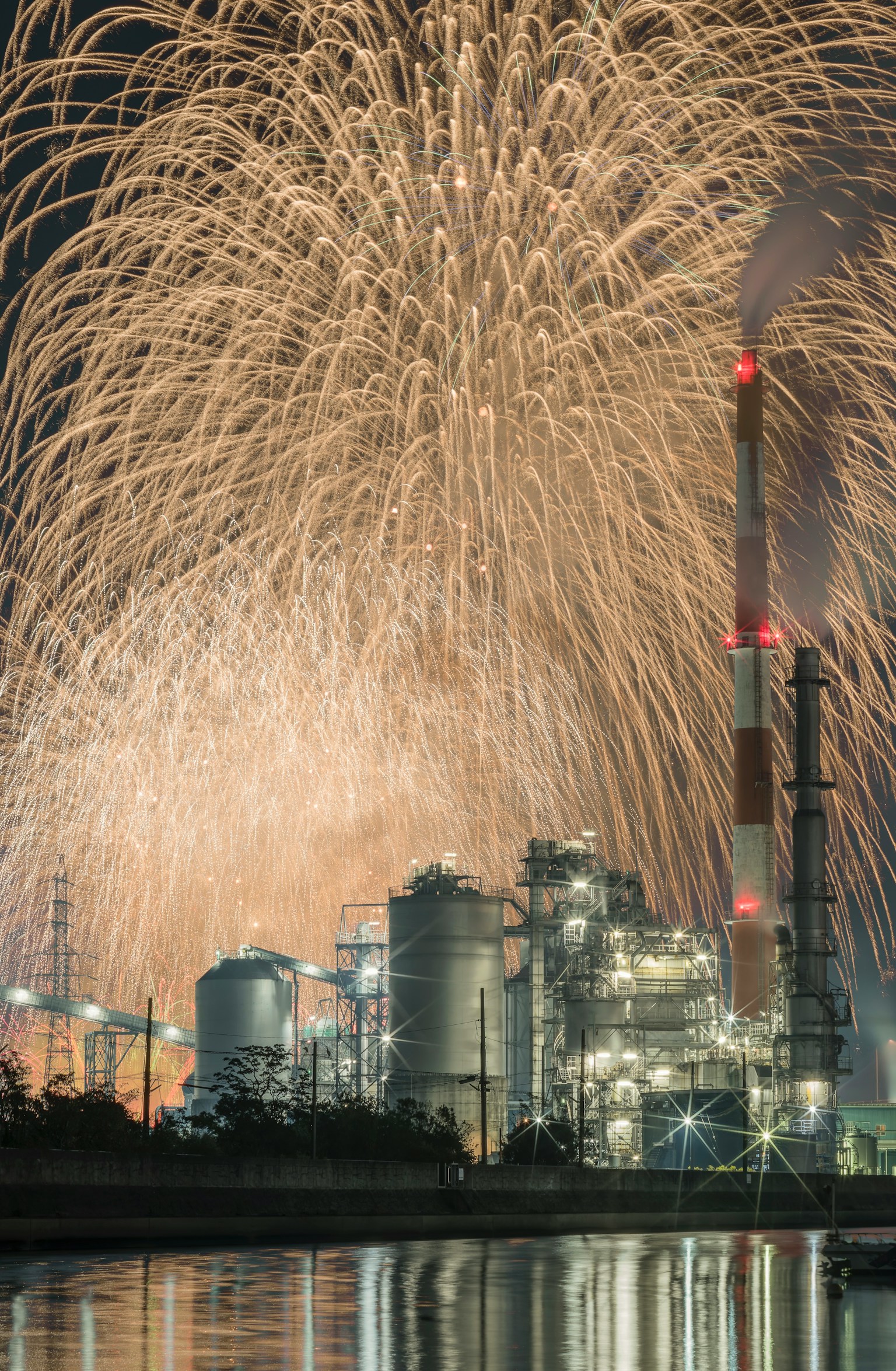 Magnifique contraste entre la silhouette d'une usine et des feux d'artifice la nuit