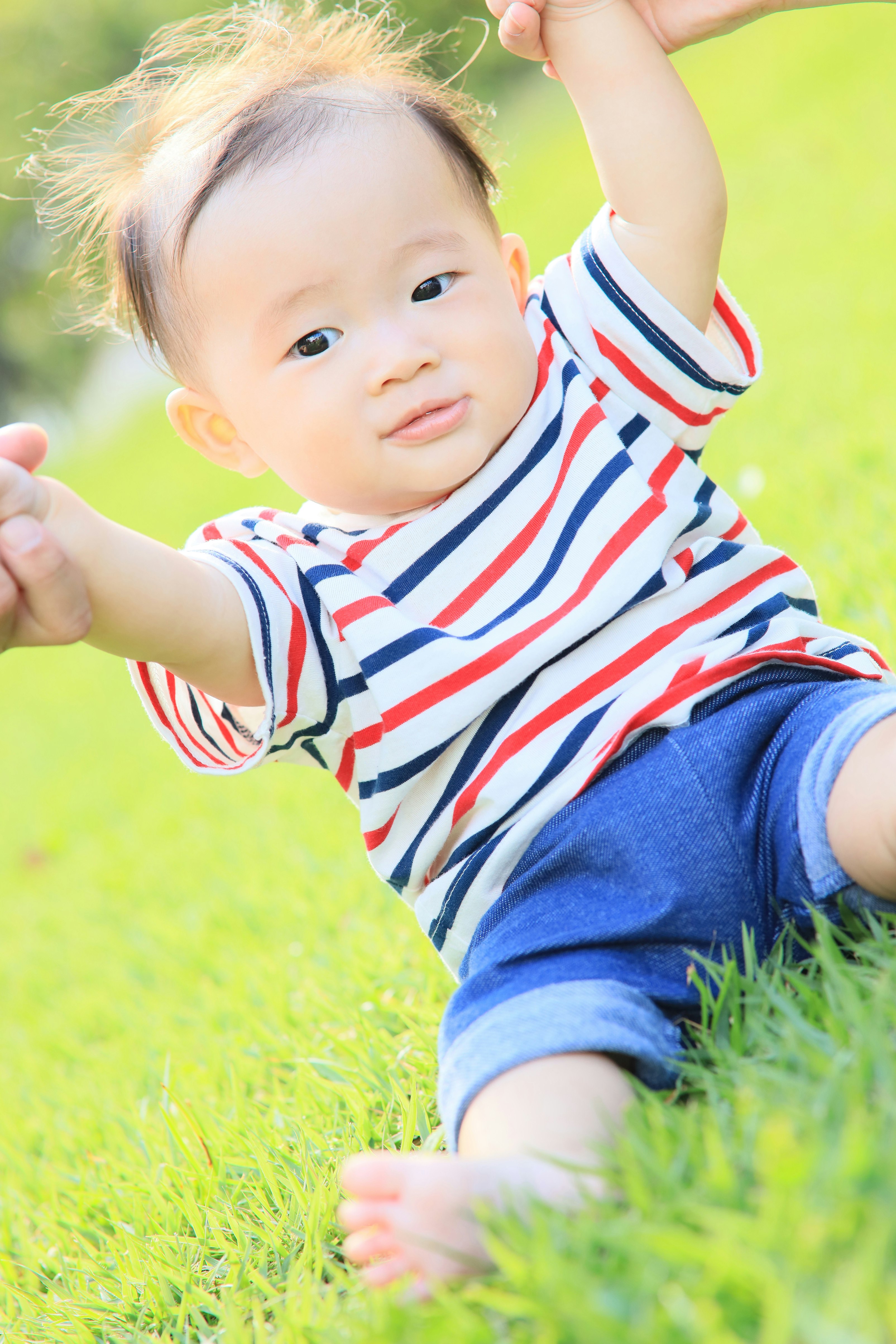 芝生の上で手を伸ばす赤ちゃん