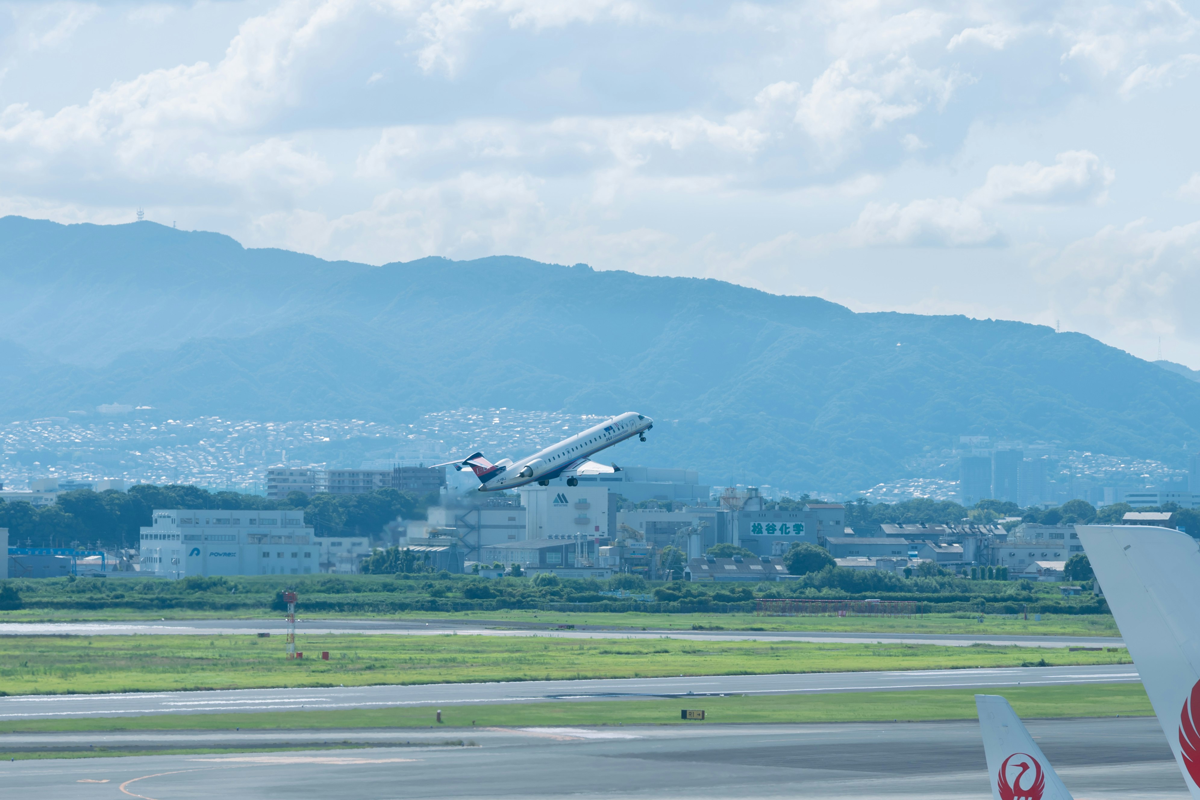 飛行機の窓から見える滑走路と山並みの風景