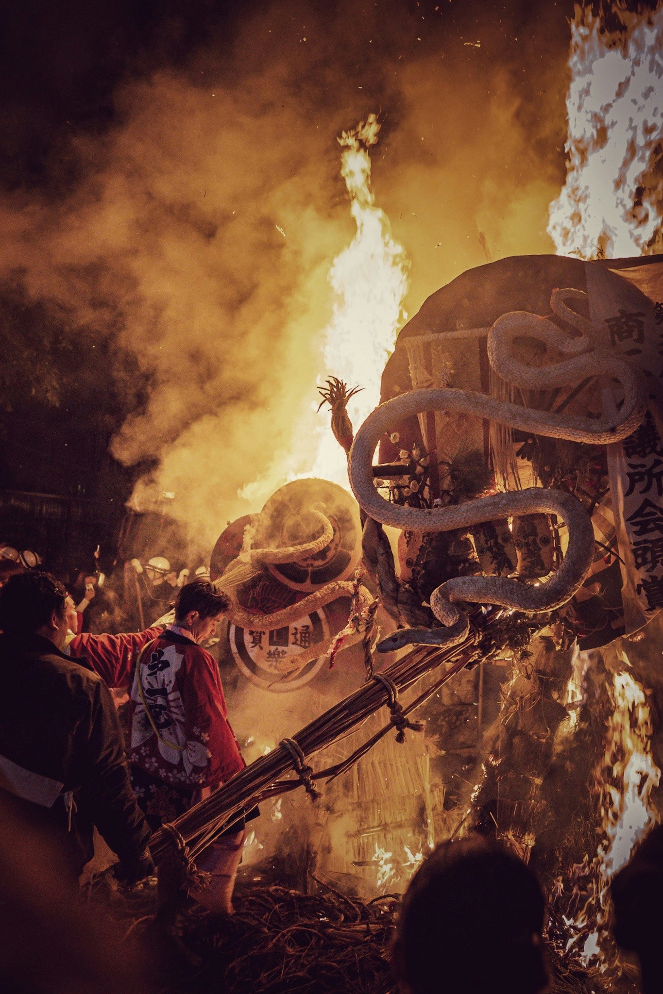 Orang membawa drum di tengah api dan asap pada Festival Sagyōchō Omi Hachiman