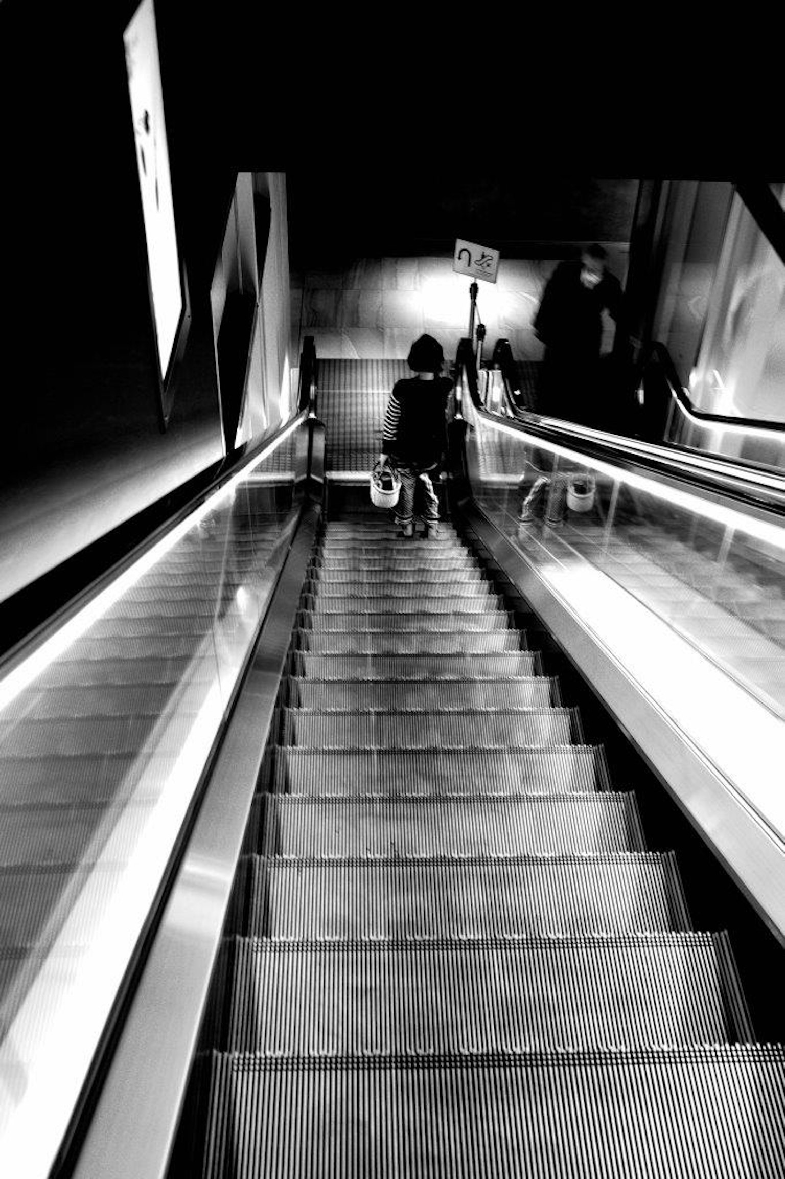 Immagine in bianco e nero di una persona che scende una scala mobile