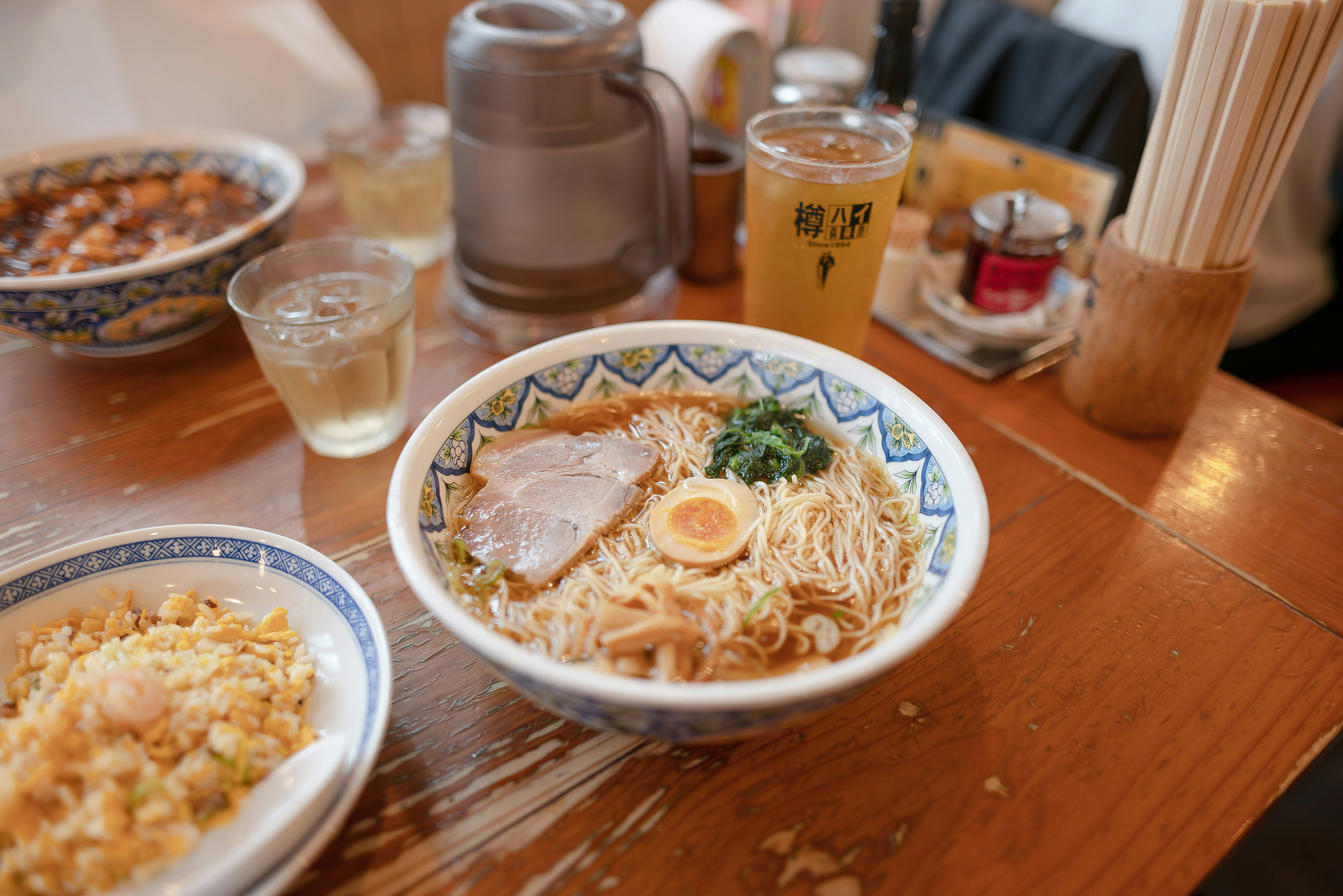 木のテーブルに並ぶラーメンとチャーハンの食事