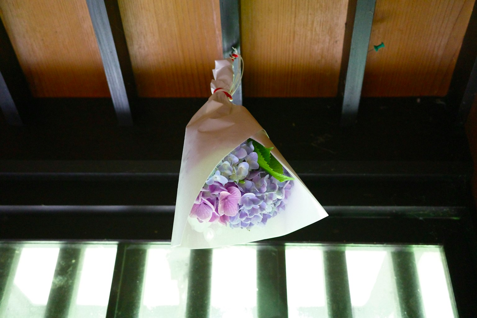 Un bouquet enveloppé dans du papier blanc suspendu à une structure en bois