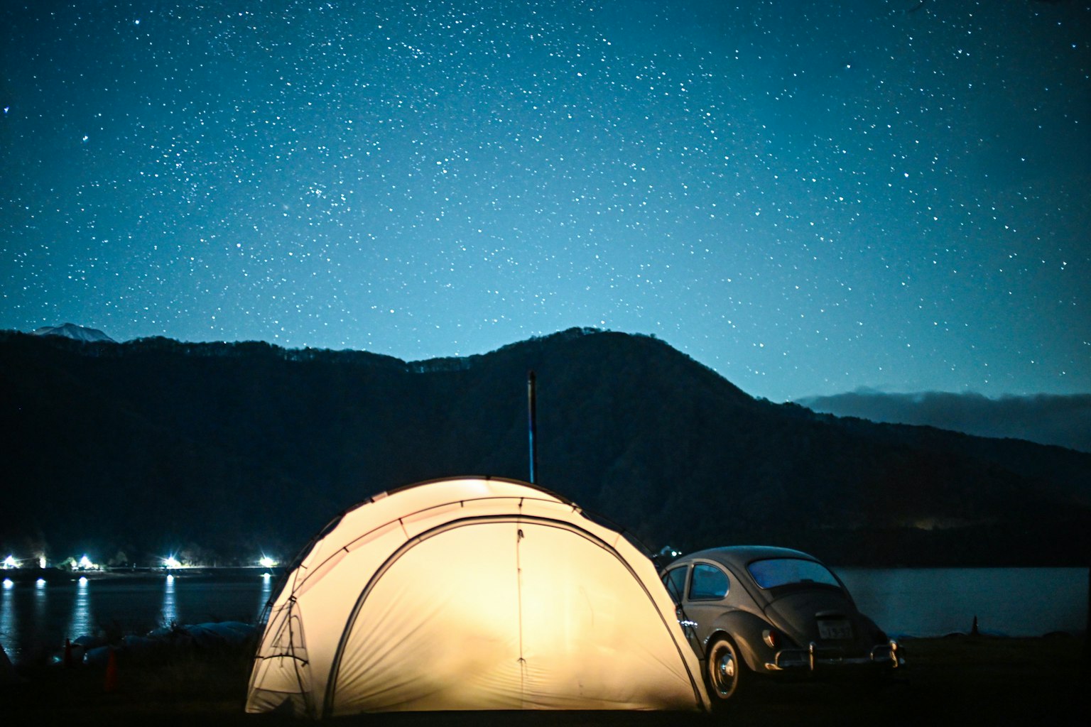 星空の下にあるテントとビートル車の風景