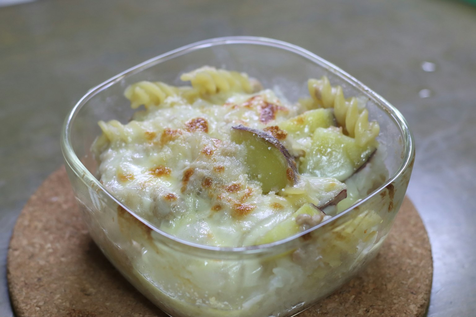 Gratin de pasta cremosa y patatas en un plato de vidrio transparente