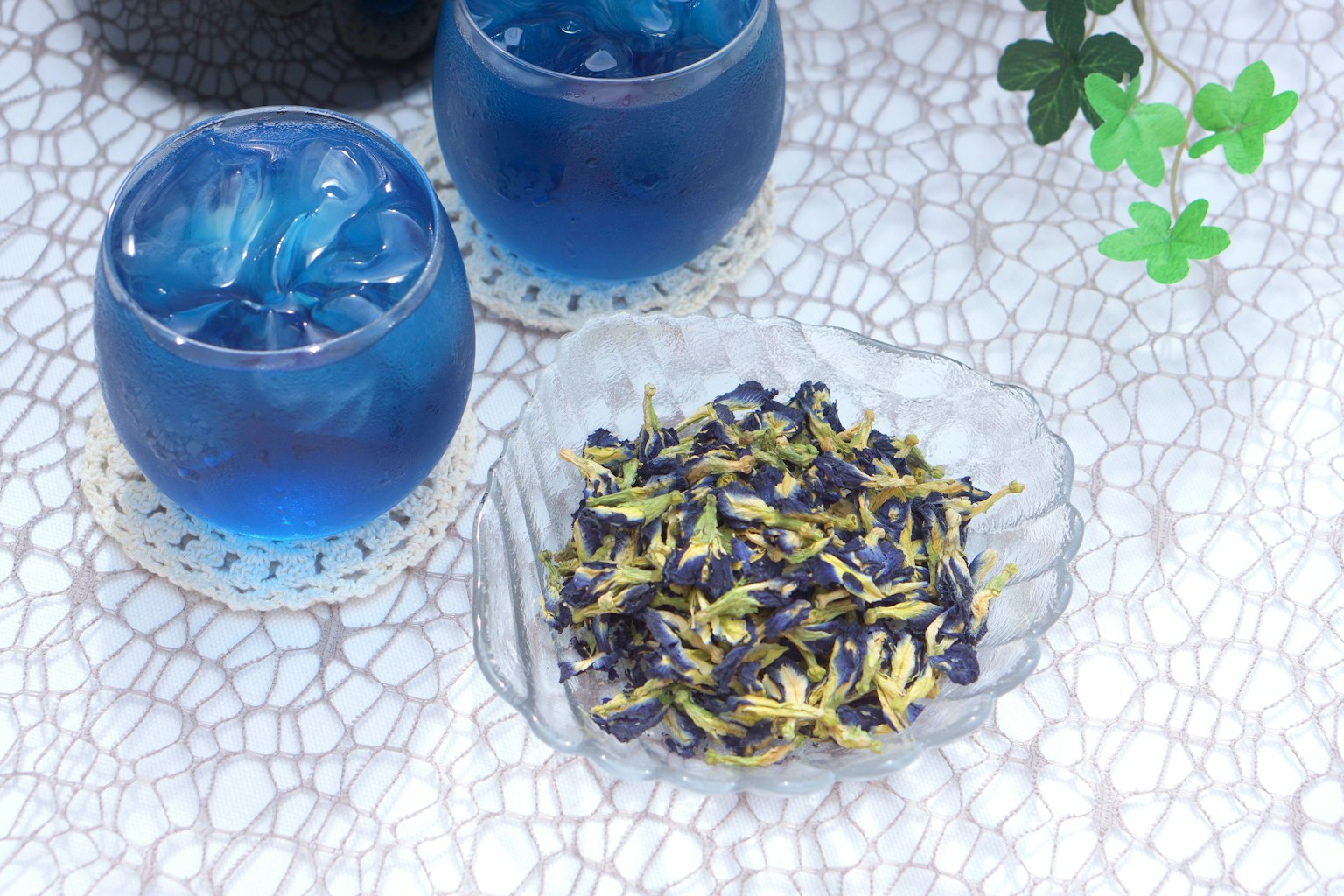 Deux boissons bleues avec de la glace et des fleurs de pois papillon séchées sur une surface texturée