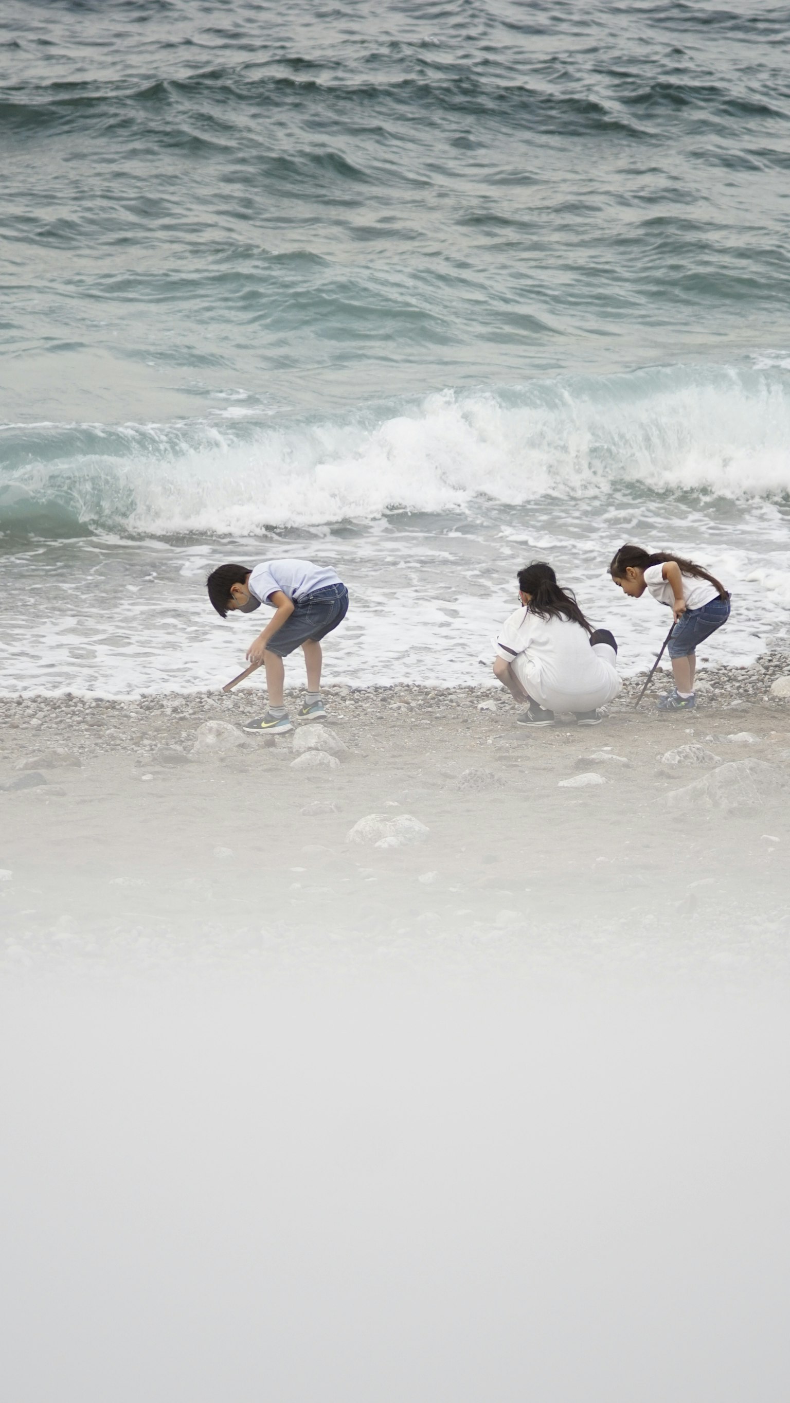 子供たちが海で遊んでいる様子で波が寄せている