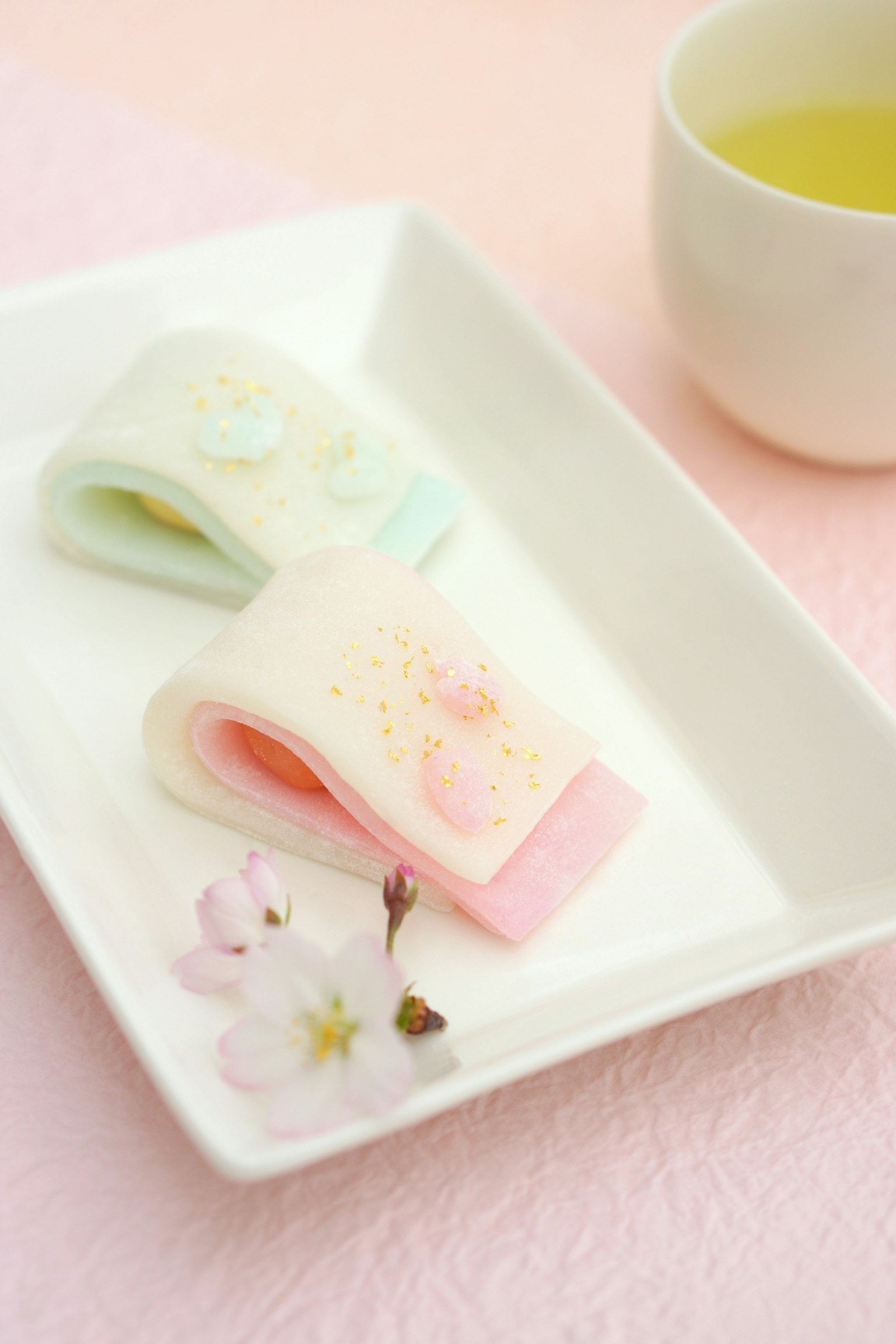 Delicate colored Japanese sweets on a plate with tea and floral decoration