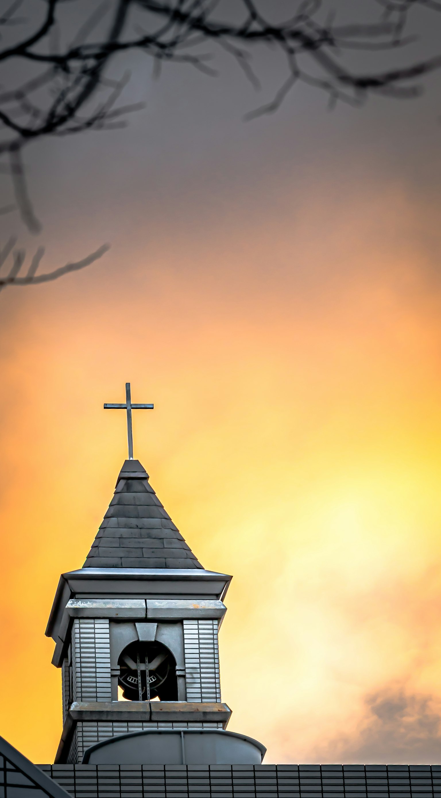 Flèche d'église avec une croix contre un ciel de coucher de soleil