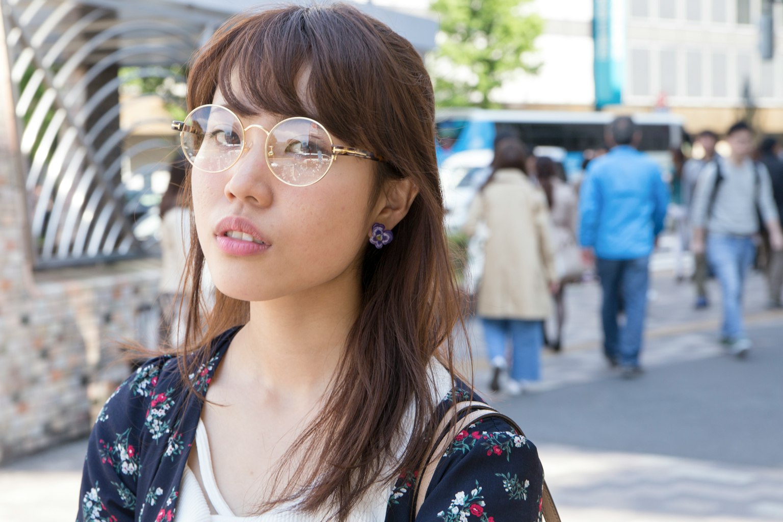 Une jeune femme portant des lunettes se tient dans une rue animée