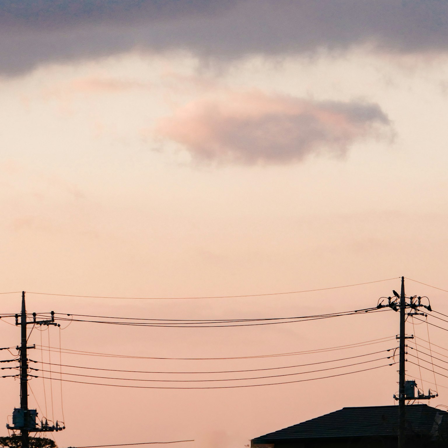 Silhouette de poteaux électriques et bâtiment contre un ciel de coucher de soleil