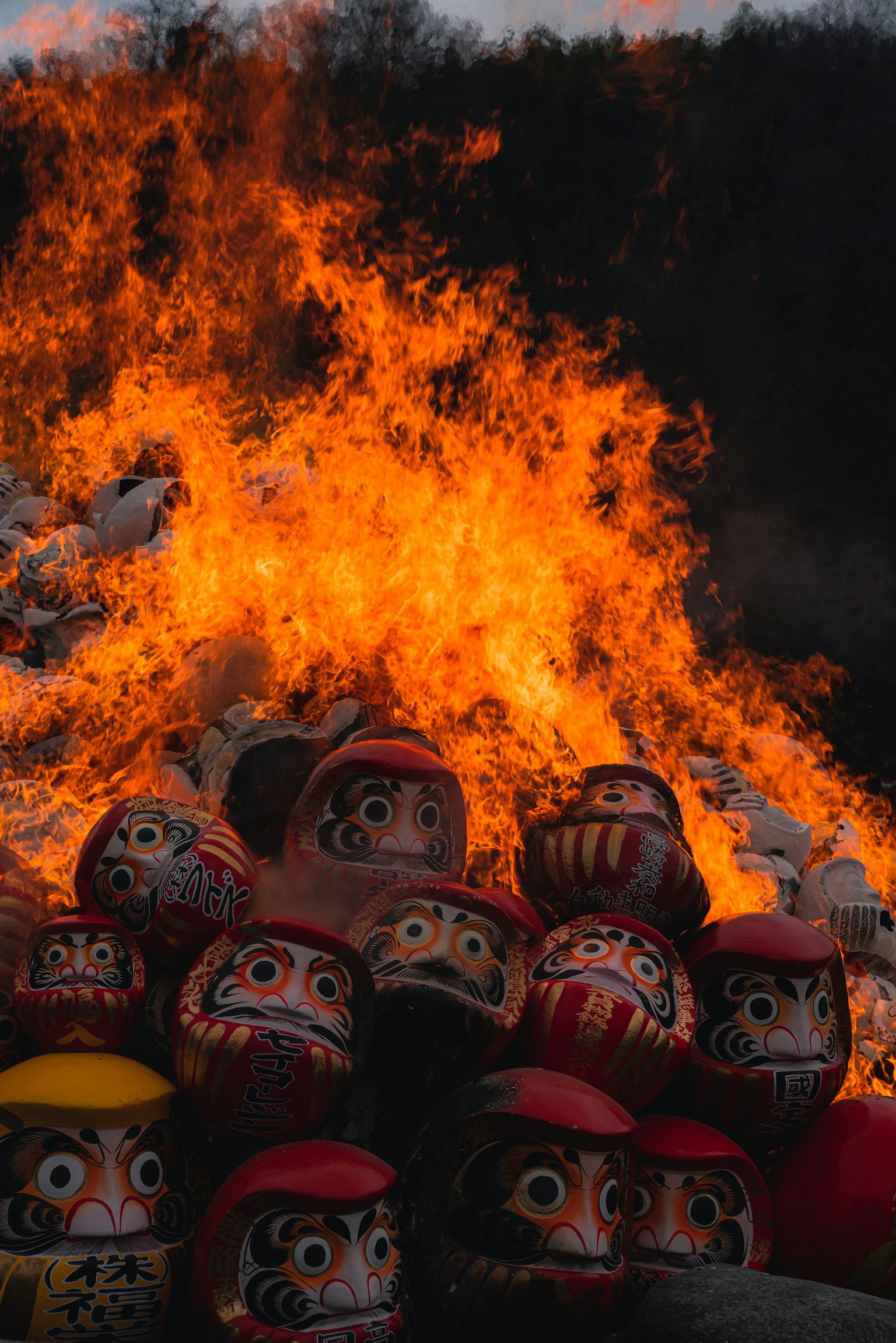 Poupées Daruma empilées devant un grand feu