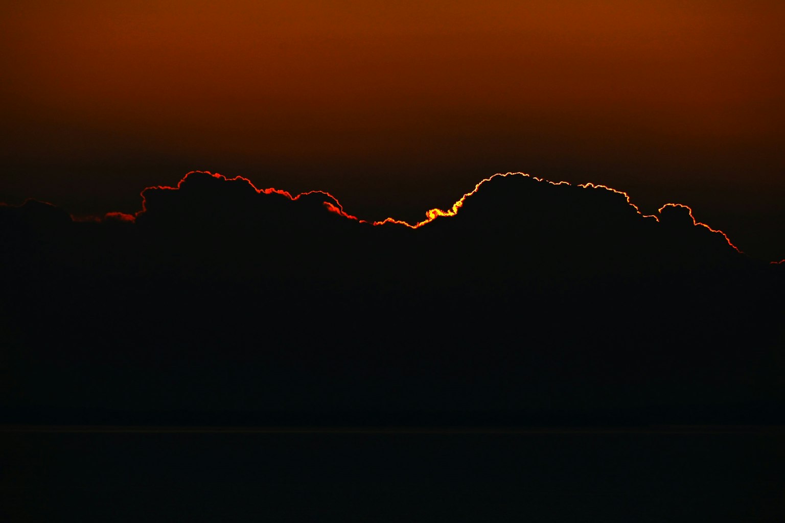 Silhouette awan di latar belakang matahari terbenam yang cerah