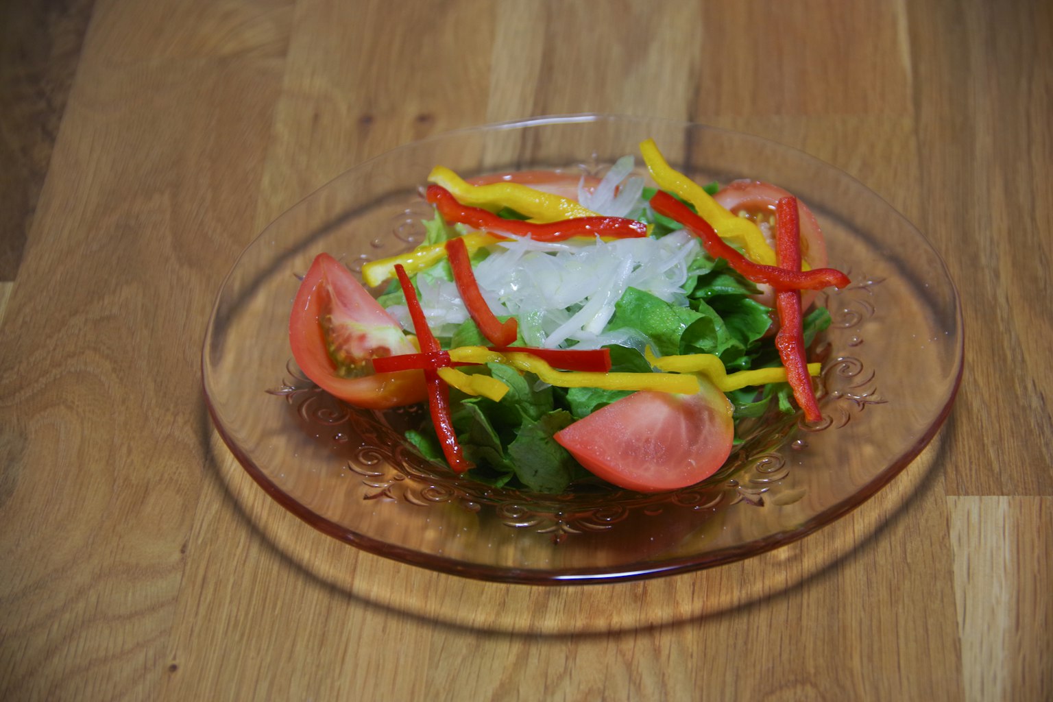 Piring salad dengan tomat yang diiris dan paprika berwarna-warni disusun menarik
