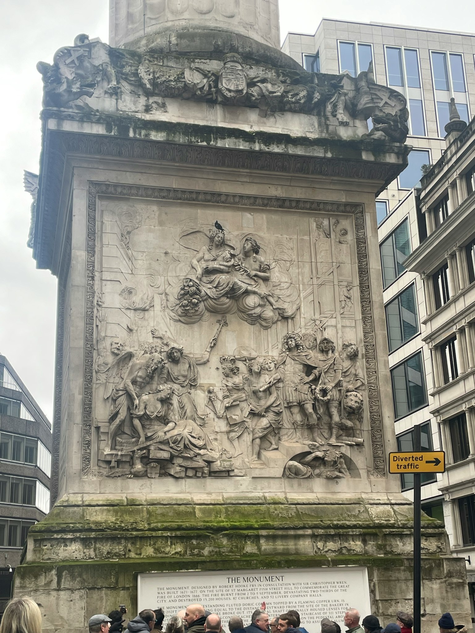 Detail einer Steinsäule mit Skulpturen an einem Monument in London umgeben von Menschen