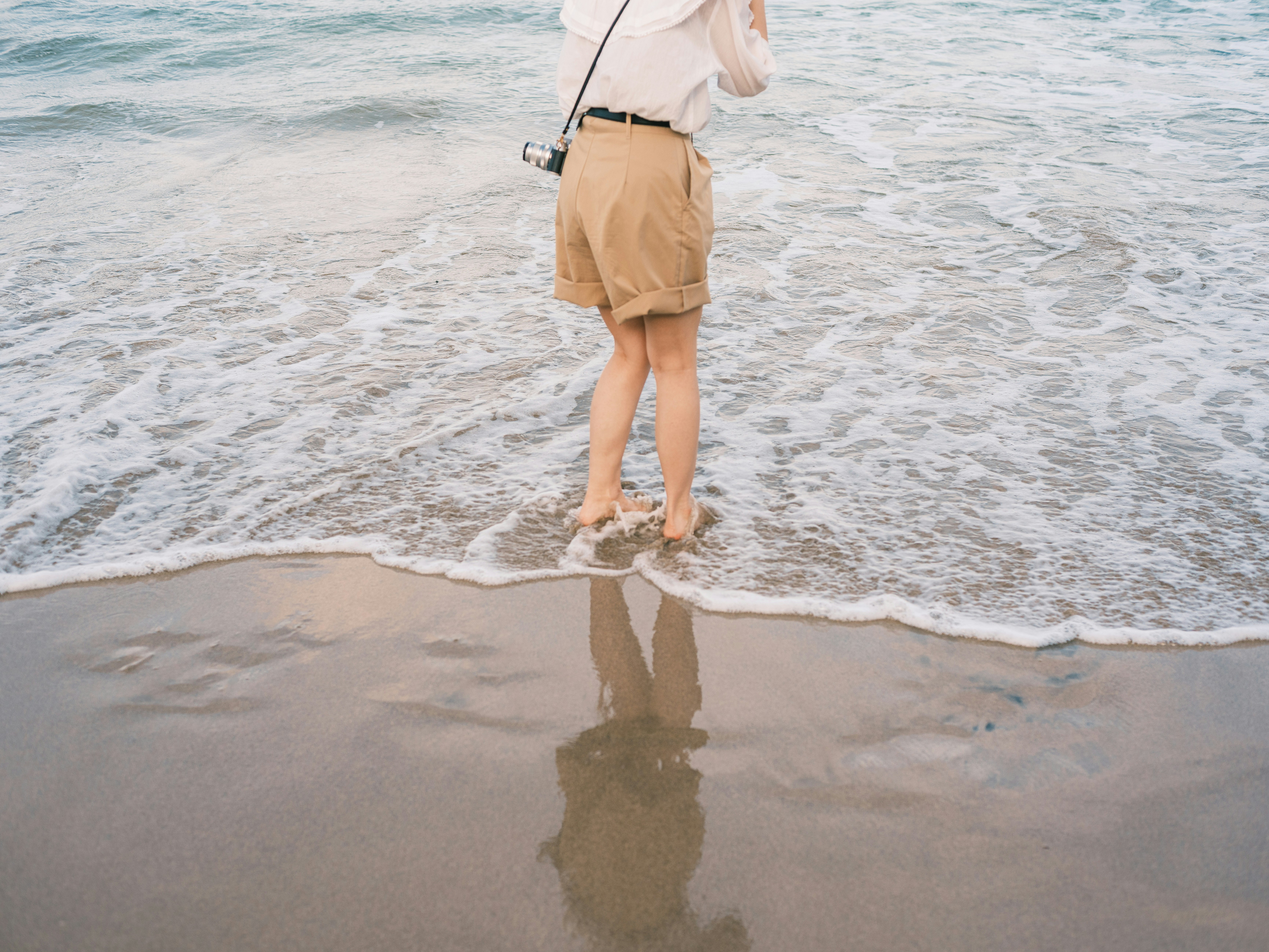 波打ち際で水しぶきを浴びる人の後ろ姿