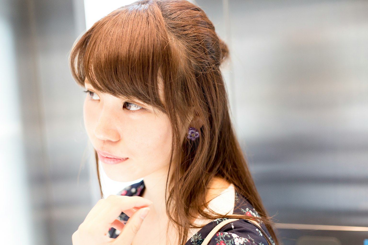 Portrait of a woman smiling in an elevator with long brown hair and wearing earrings