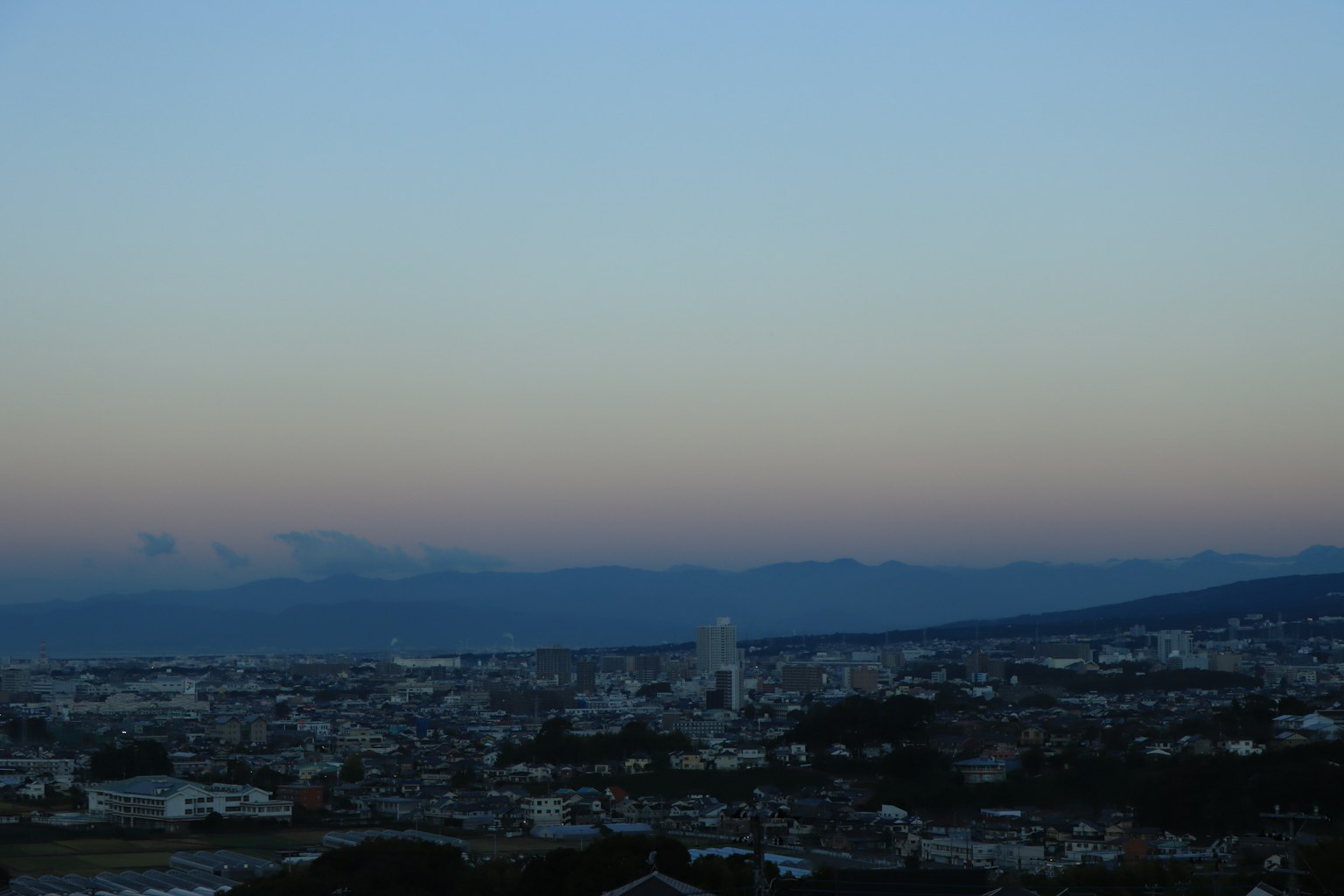Städtische Landschaft in der Dämmerung mit Bergen im Hintergrund
