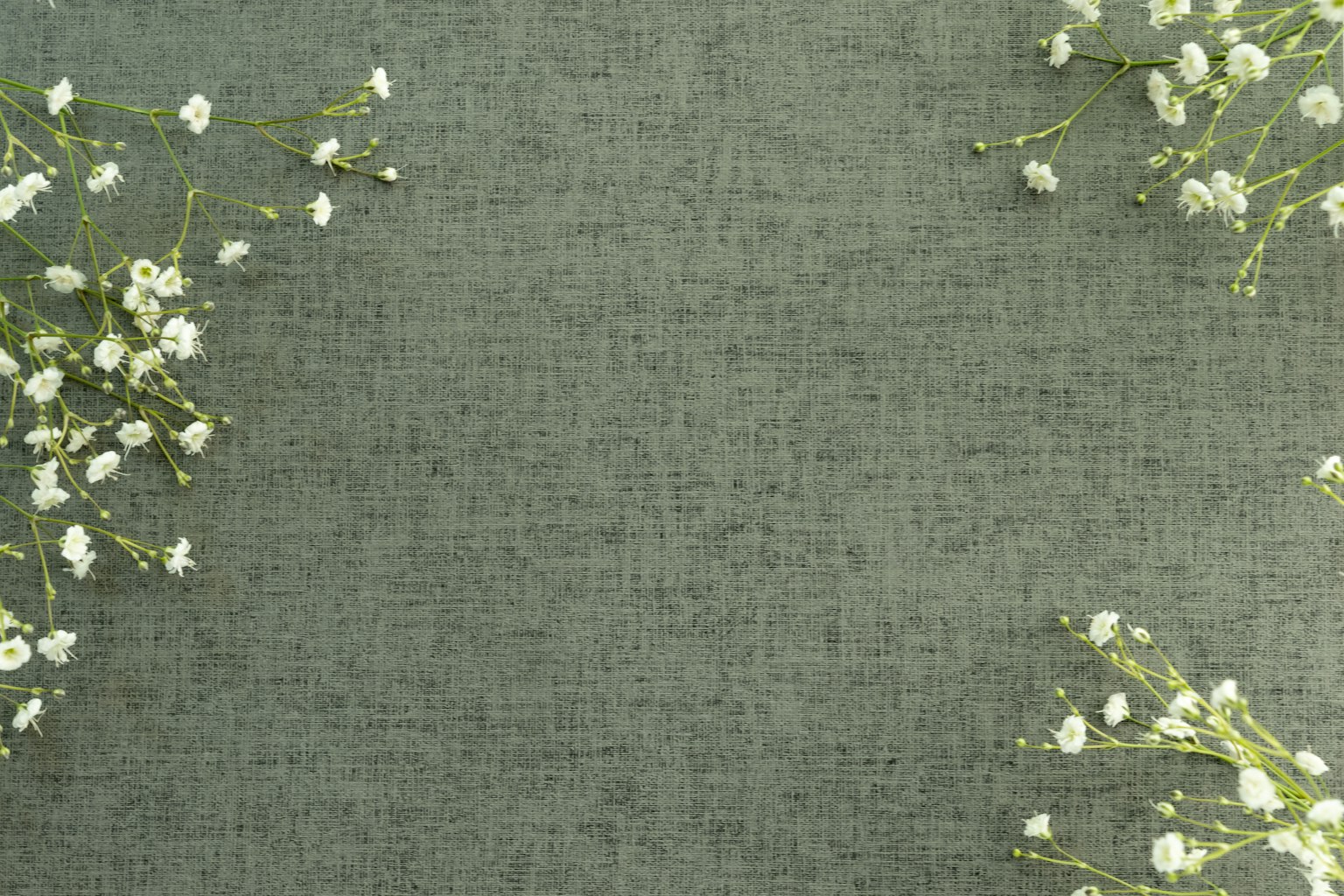 A soft green fabric background with small white flowers scattered around