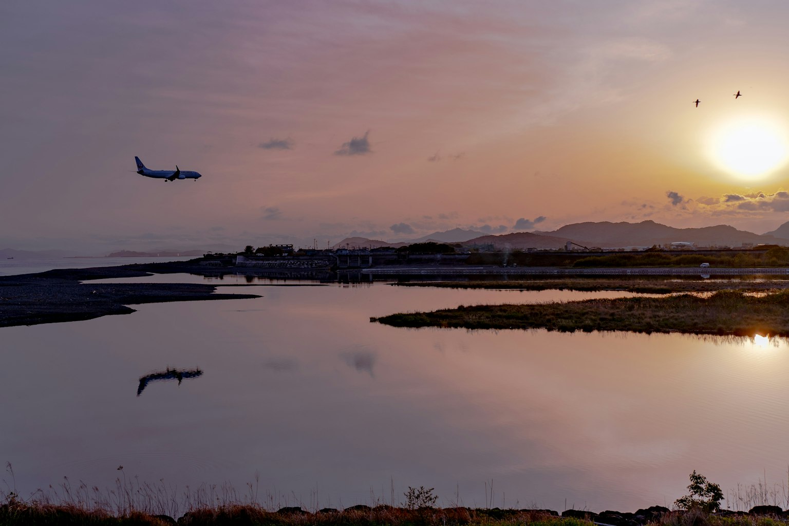 Aereo che vola al tramonto con riflesso sull'acqua calma