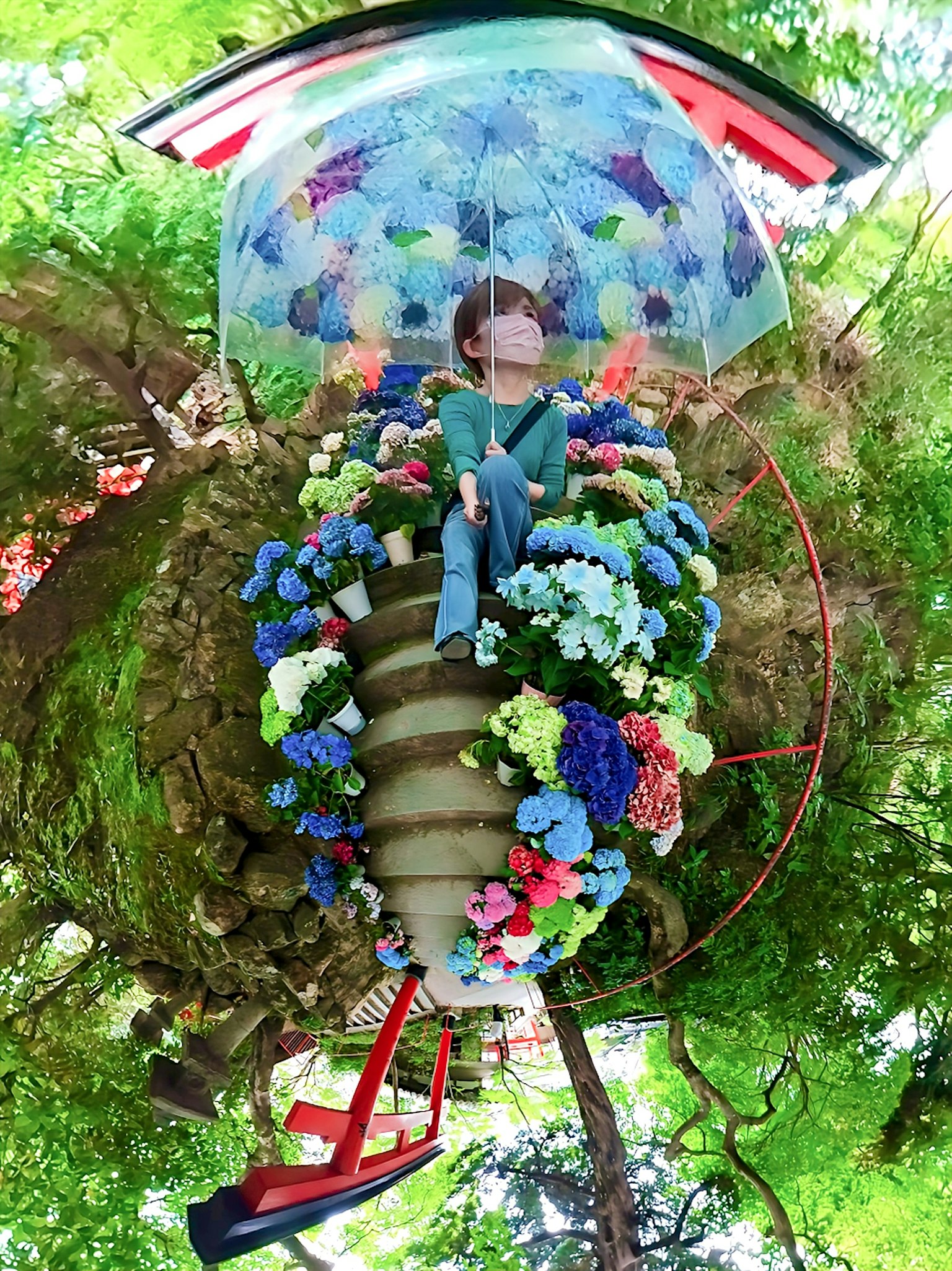 Una persona seduta sotto un ombrello colorato circondata da fiori in un ambiente fantastico