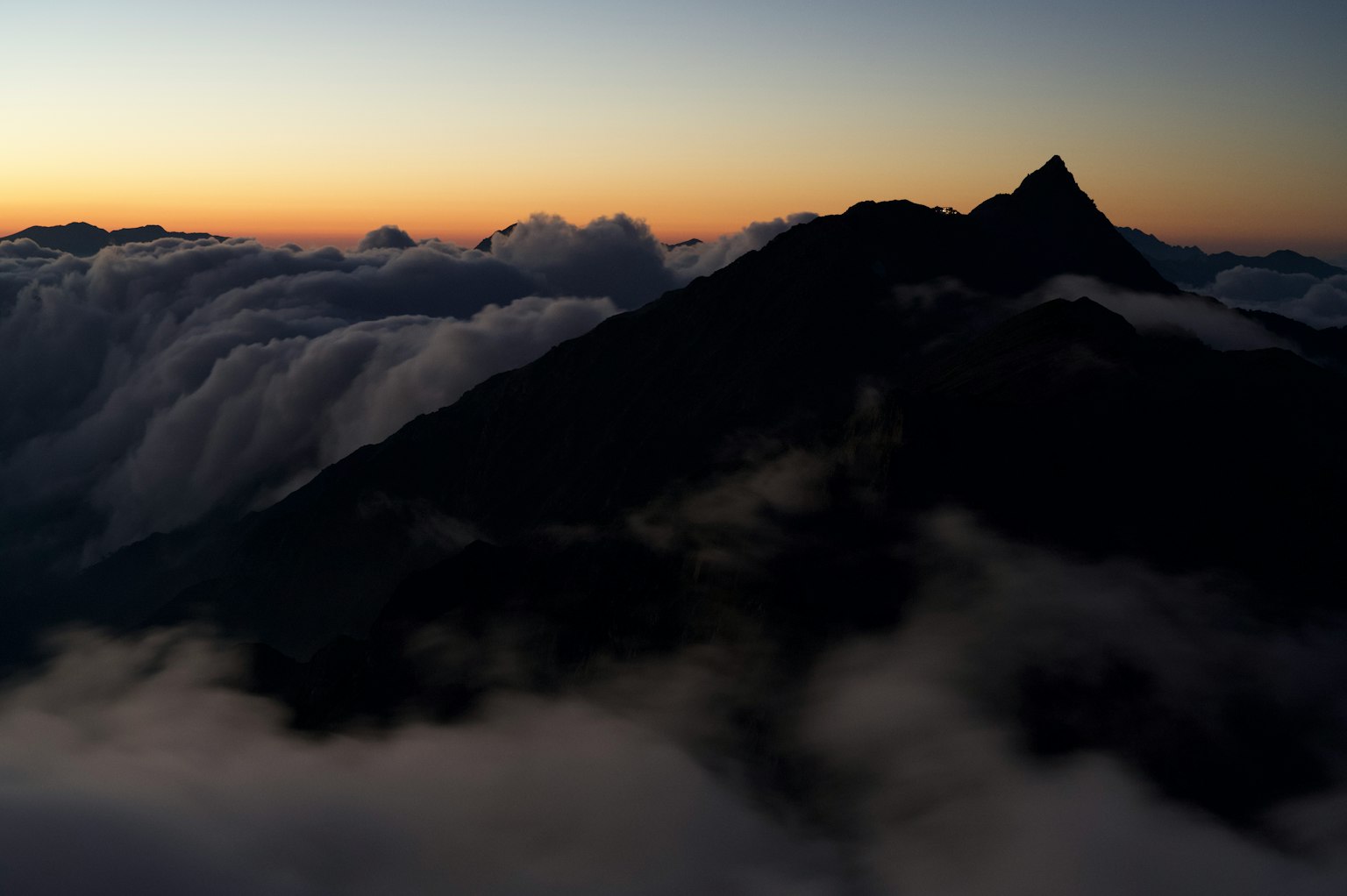 雲層上方的山脈輪廓與日落天空
