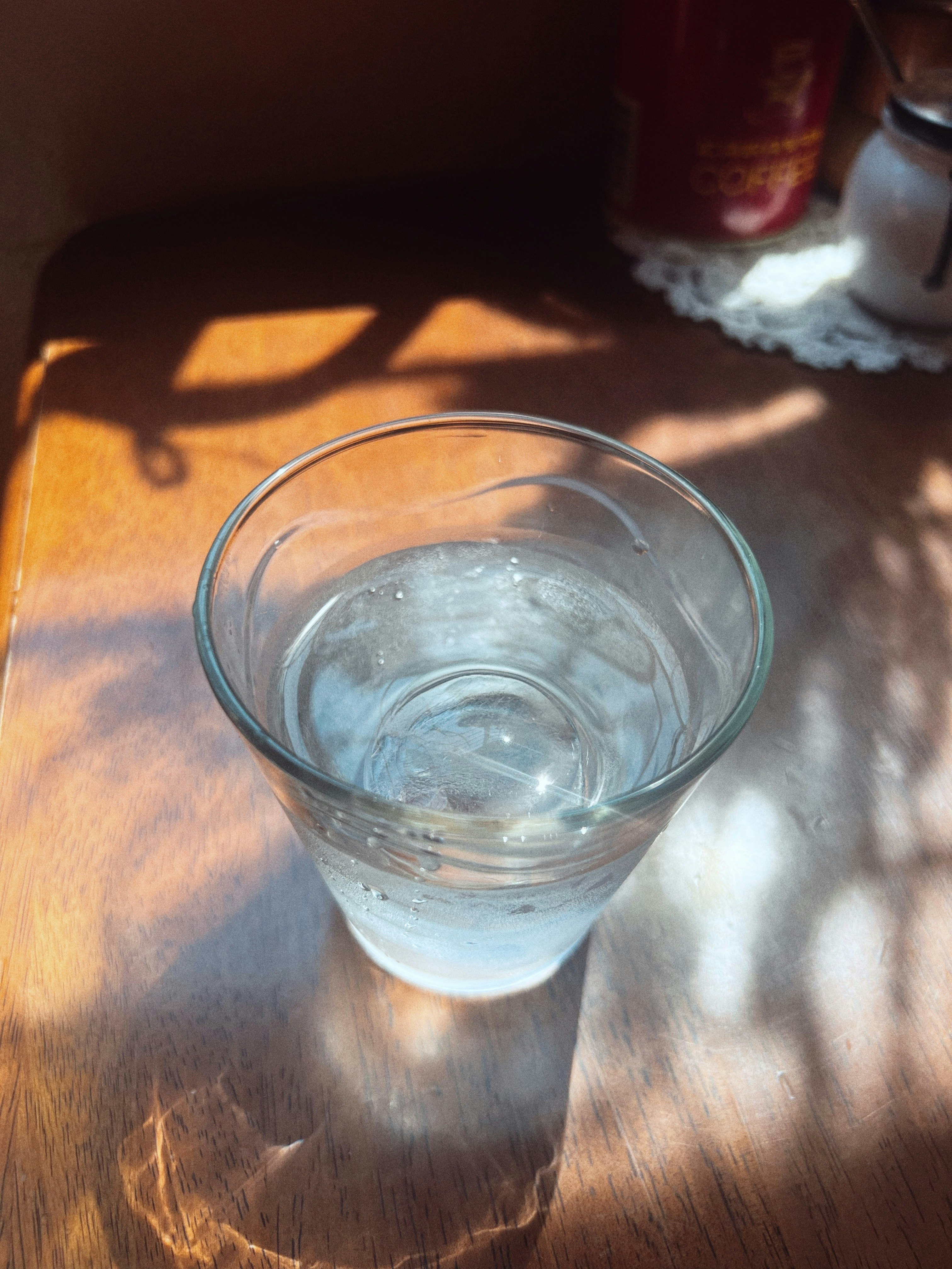 日差しの下のコップに入った氷の水