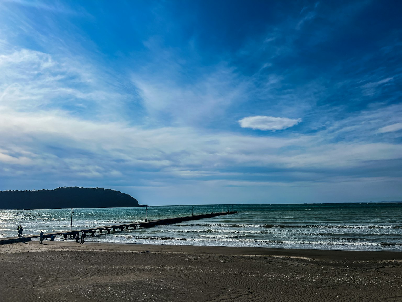 Vista panoramica del cielo blu e dell'oceano con nuvole bianche e un molo