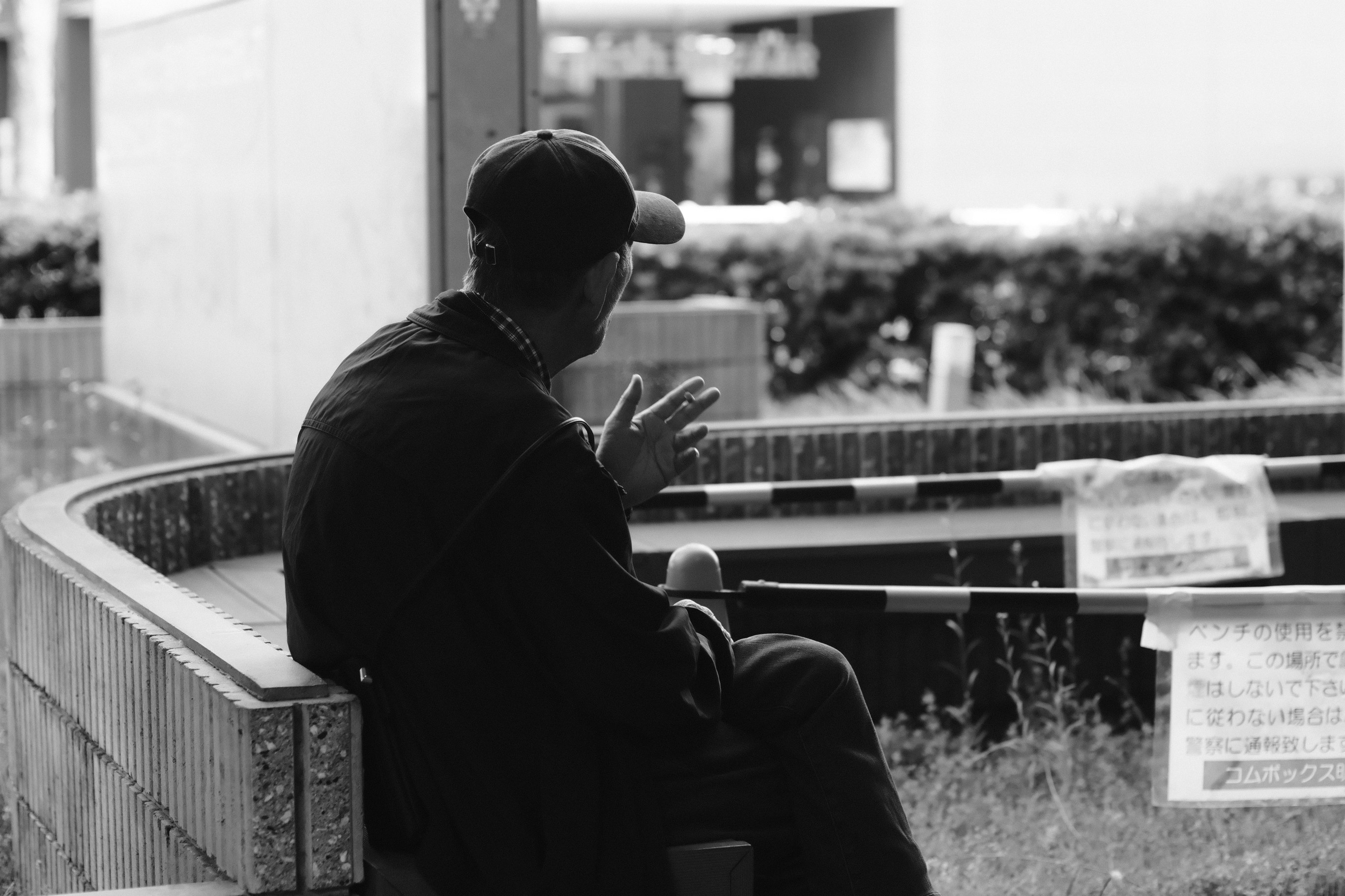 escena en blanco y negro: una persona sentada en un banco con las manos juntas
