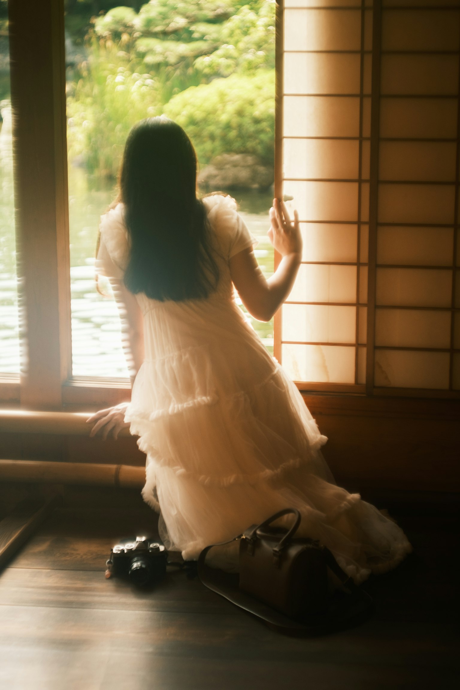 Una donna in abito bianco seduta vicino a una finestra di spalle Capelli neri lunghi Luce naturale in una stanza giapponese tradizionale
