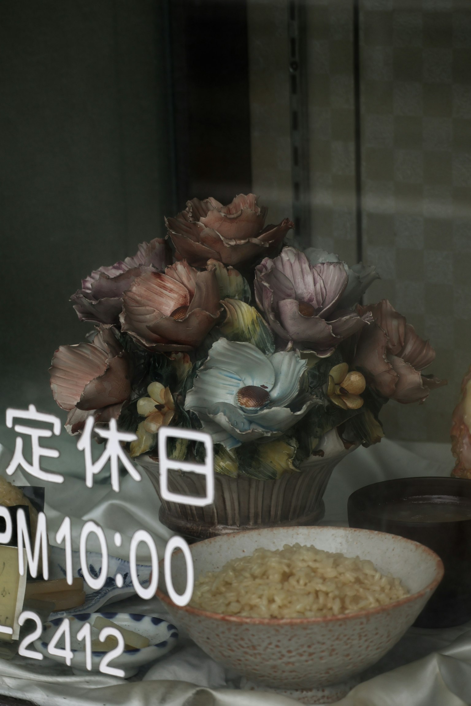 Schaufenster mit Blumenarrangement und einer Schüssel Essen