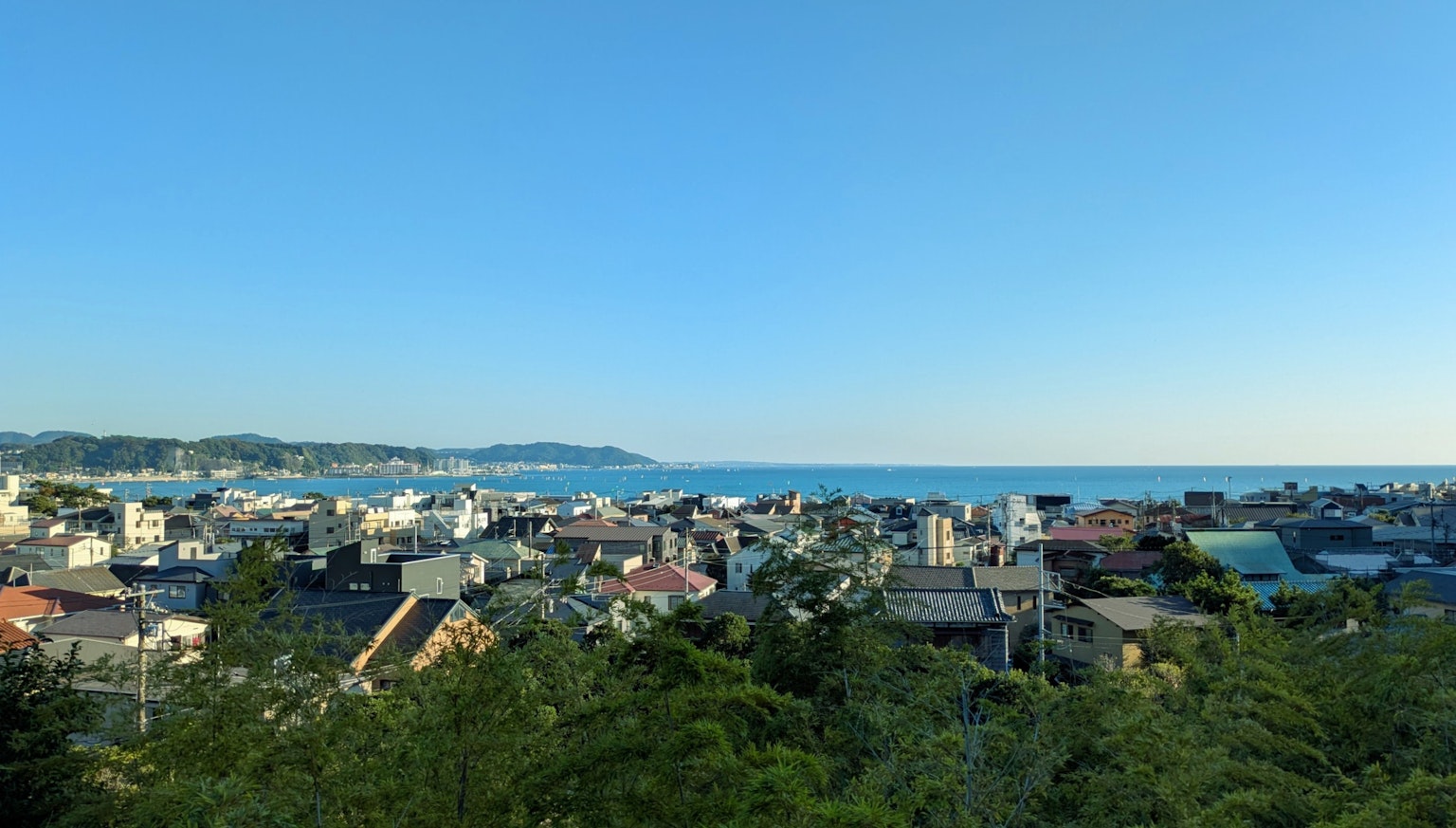 Vista panoramica di una città costiera con cielo blu e vegetazione