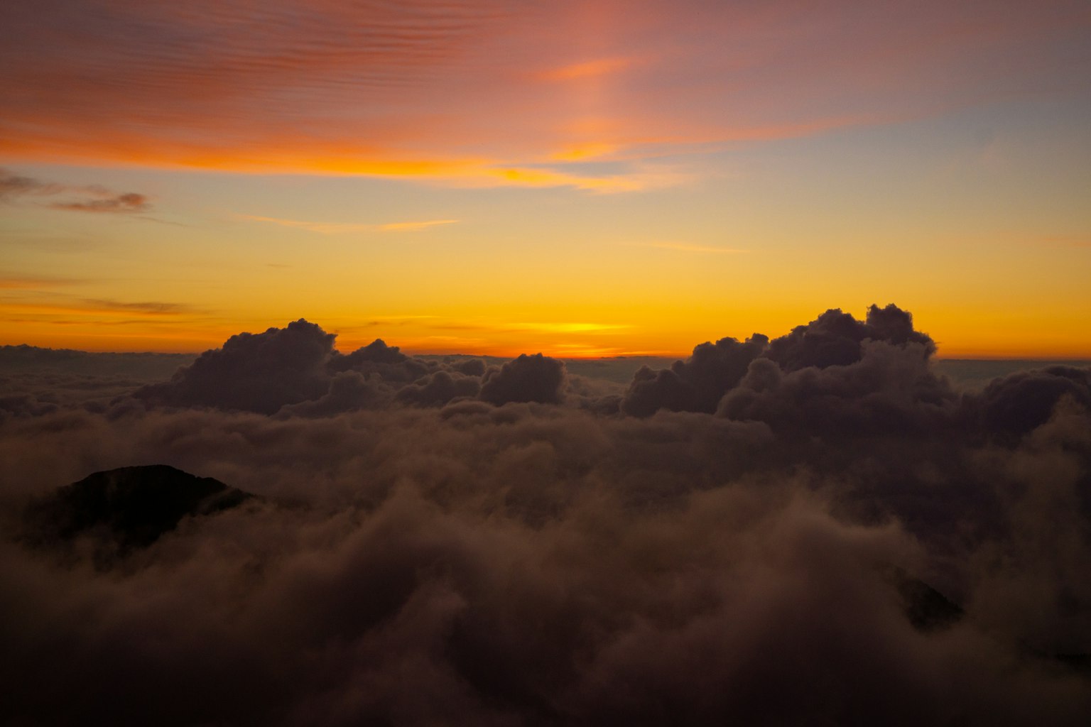 Cielo al tramonto sopra le nuvole con silhouette di montagna