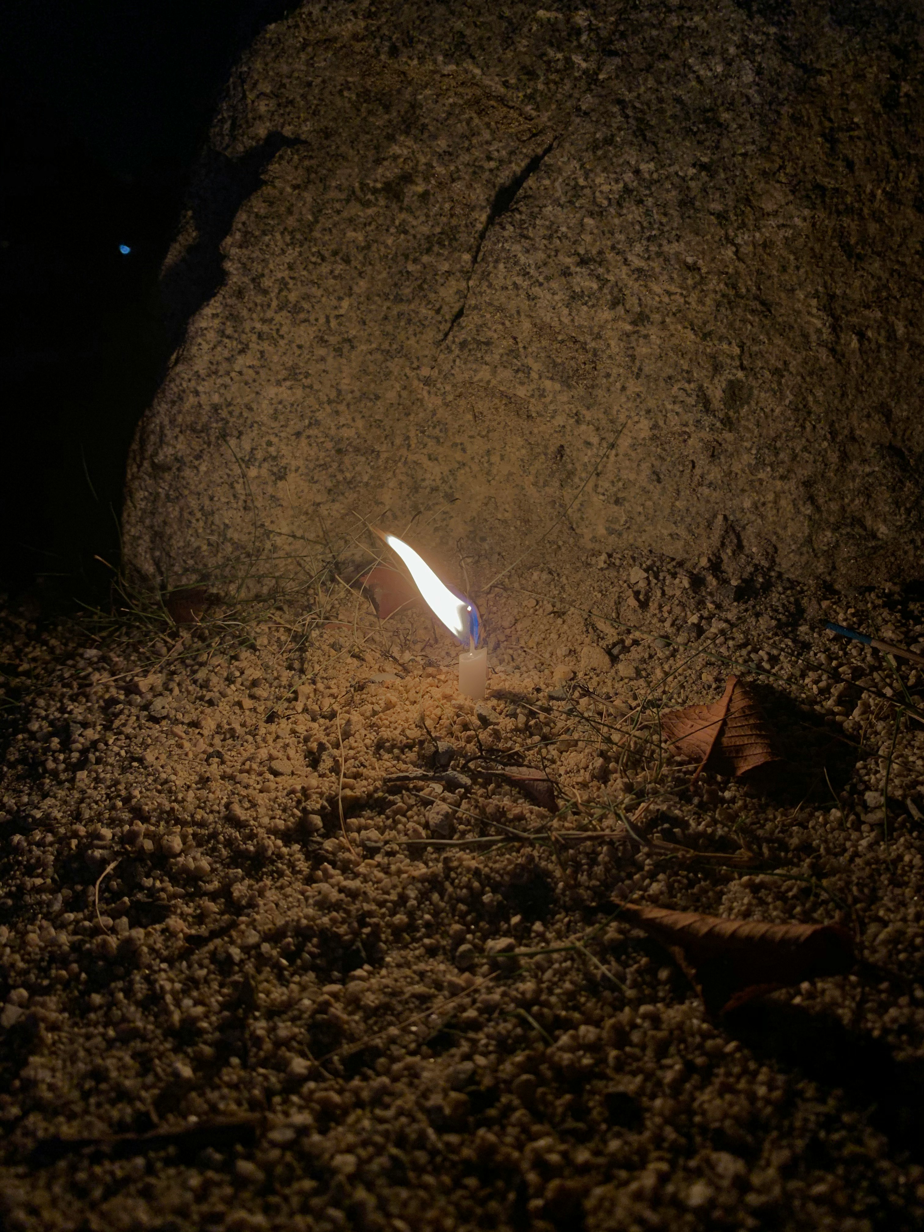夜の砂地に光る小さな炎と煙のある焚き火のようなシーン