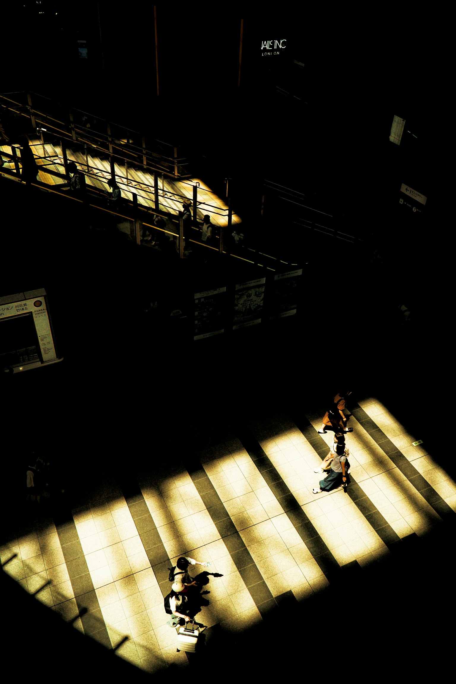 Silhouettes de personnes marchant dans un espace sombre illuminé par la lumière
