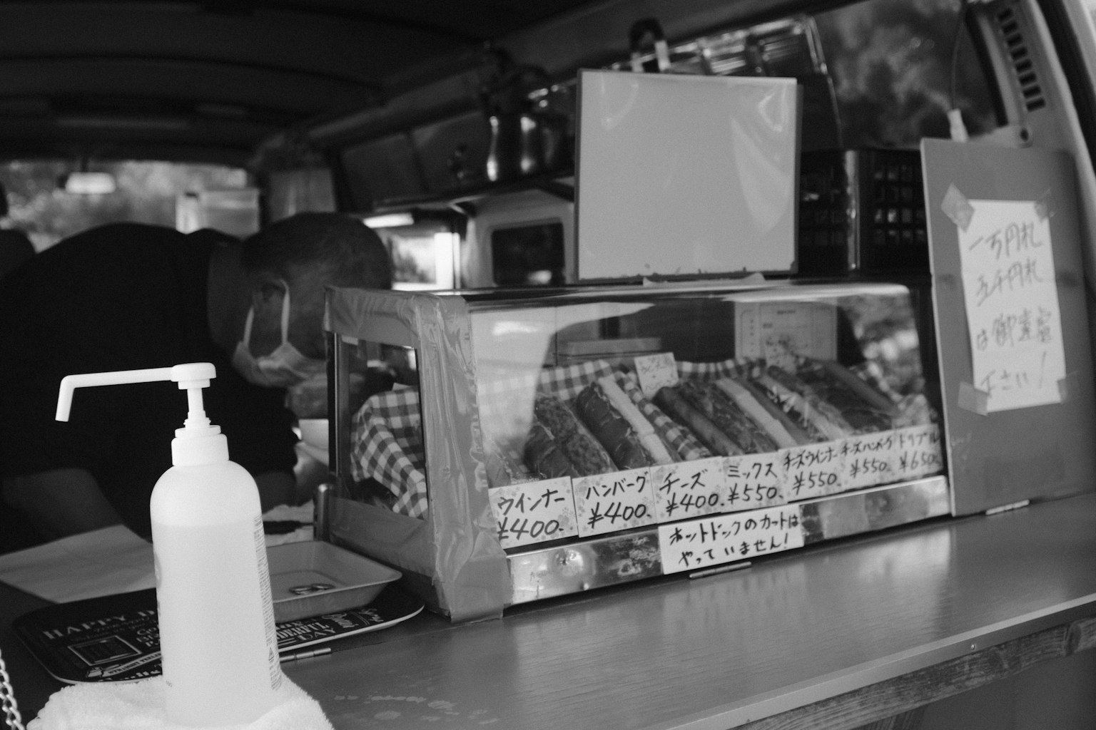 屋台の中で食べ物を準備している人とガラスケースに並ぶ食べ物