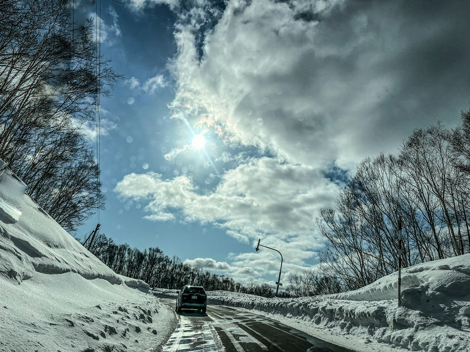 汽車在雪覆蓋的道路上行駛，藍天之下