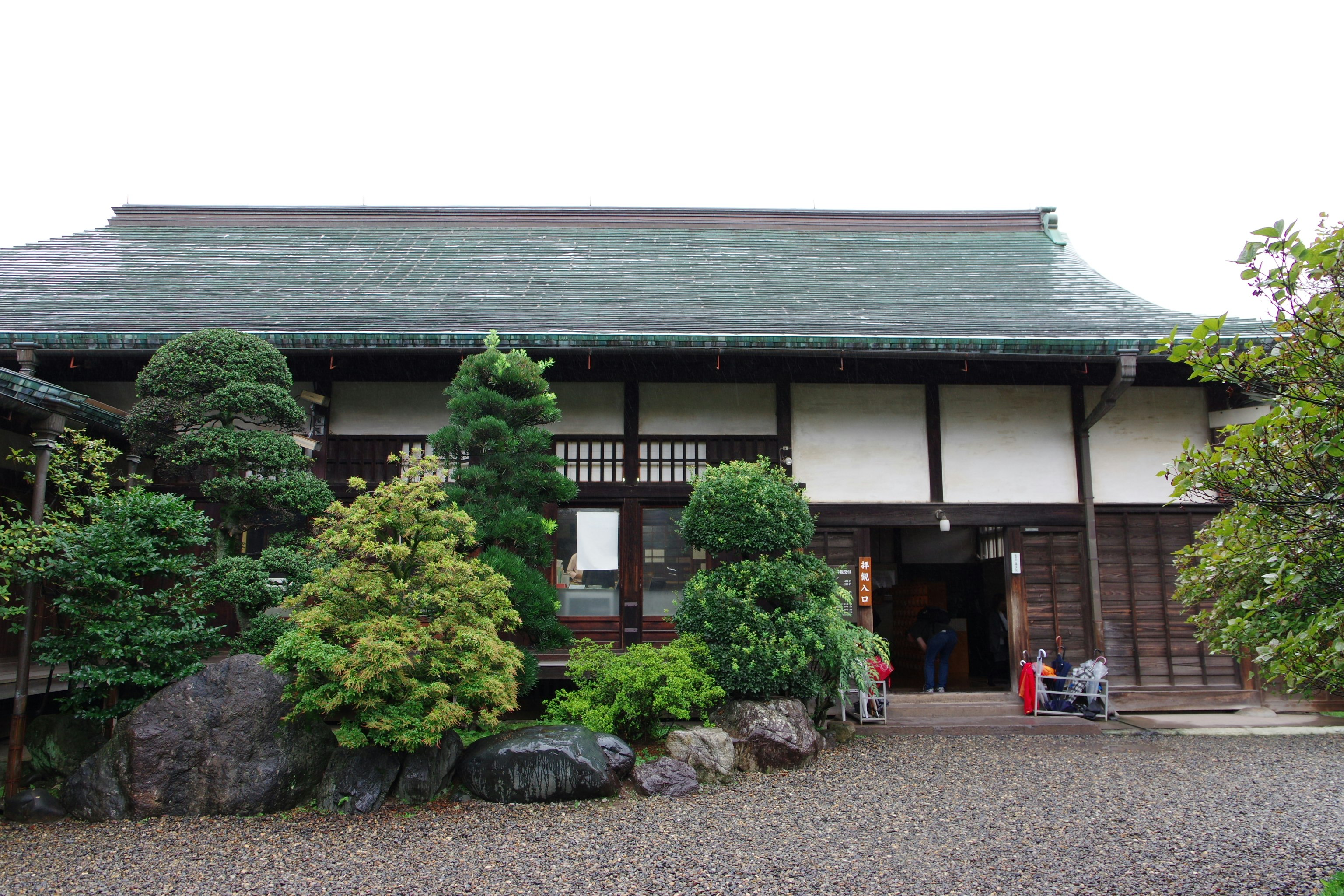 Japanese-style building entrance with garden stones and mossy trees