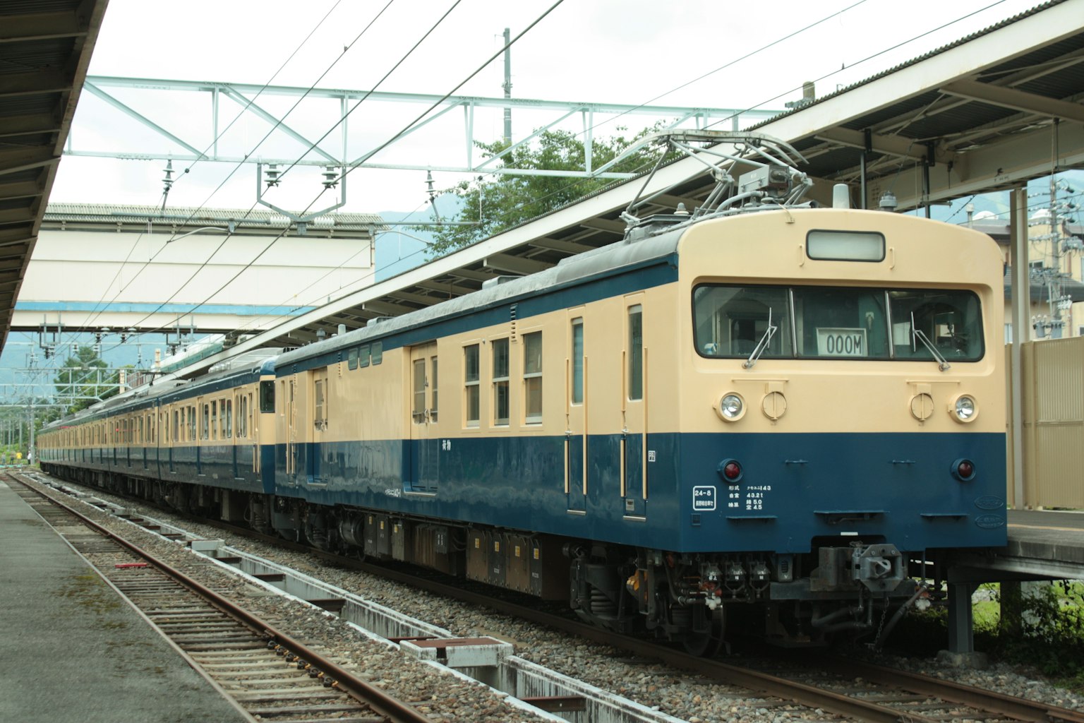 Un tren eléctrico azul y crema está detenido en una estación