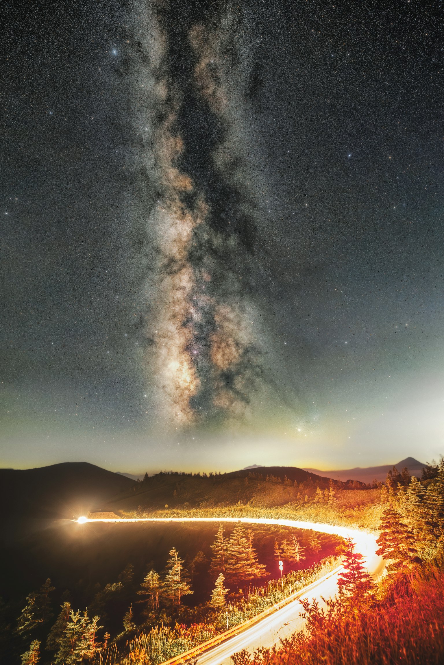 Paysage avec la Voie lactée et des traînées de lumière de voiture sous un ciel étoilé