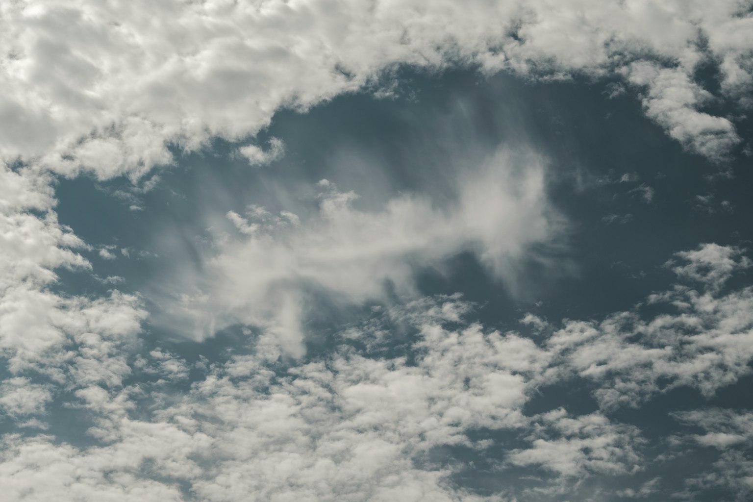 Celah di awan yang mengungkapkan langit biru dengan pola awan putih