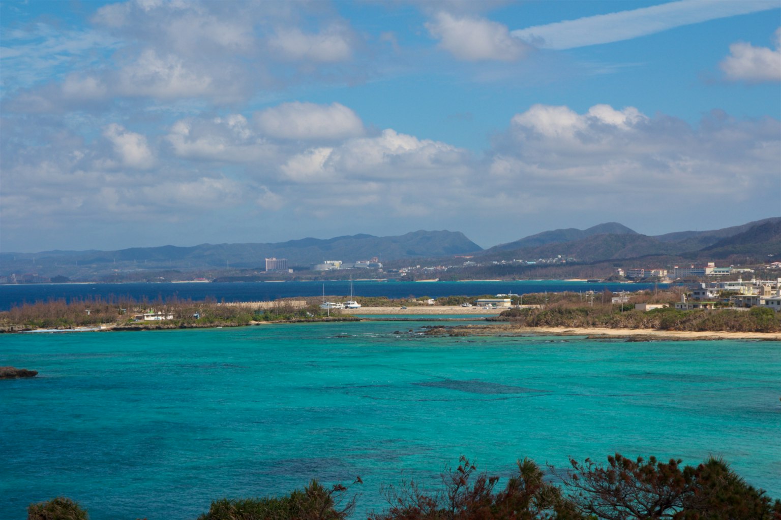 ทิวทัศน์ที่น่าทึ่งของน้ำสีฟ้าและภูเขา沿沖繩海岸