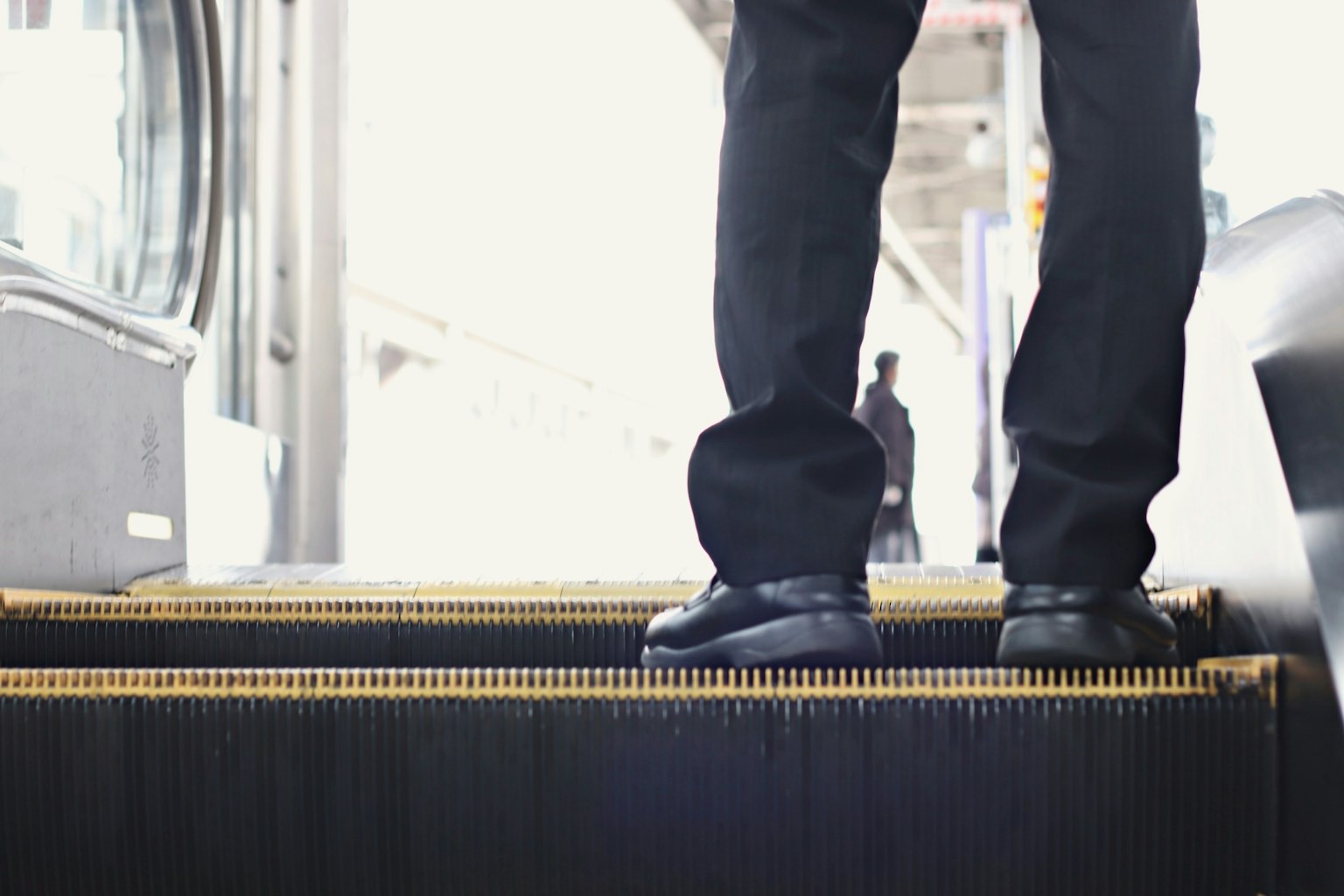 Pieds d'un homme sur des escaliers, portant un costume d'affaires, arrière-plan de gare