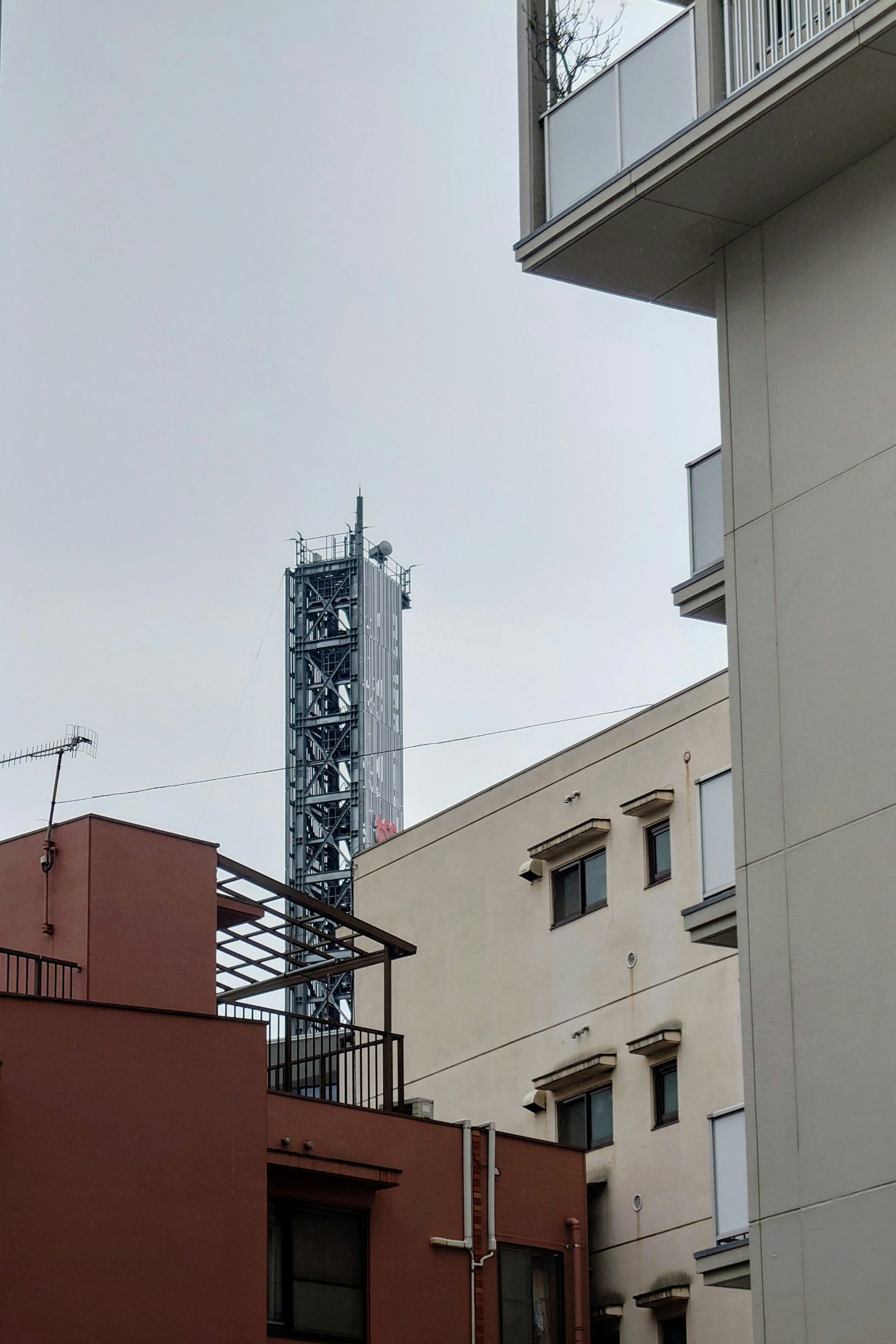 Kommunikationsturm zwischen Gebäuden unter einem bewölkten Himmel sichtbar