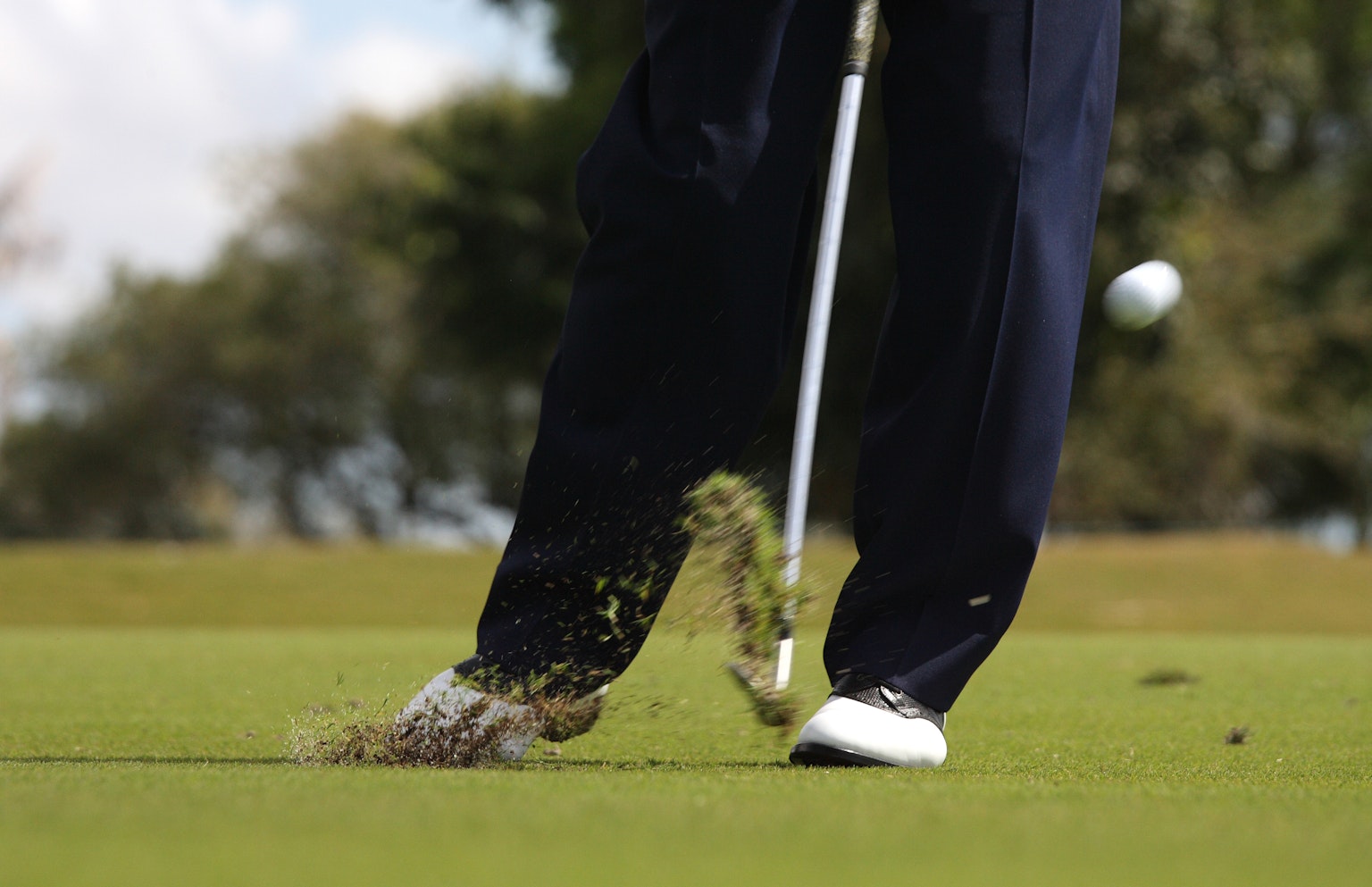Primo piano di un golfista che colpisce la palla con un bastone su erba verde