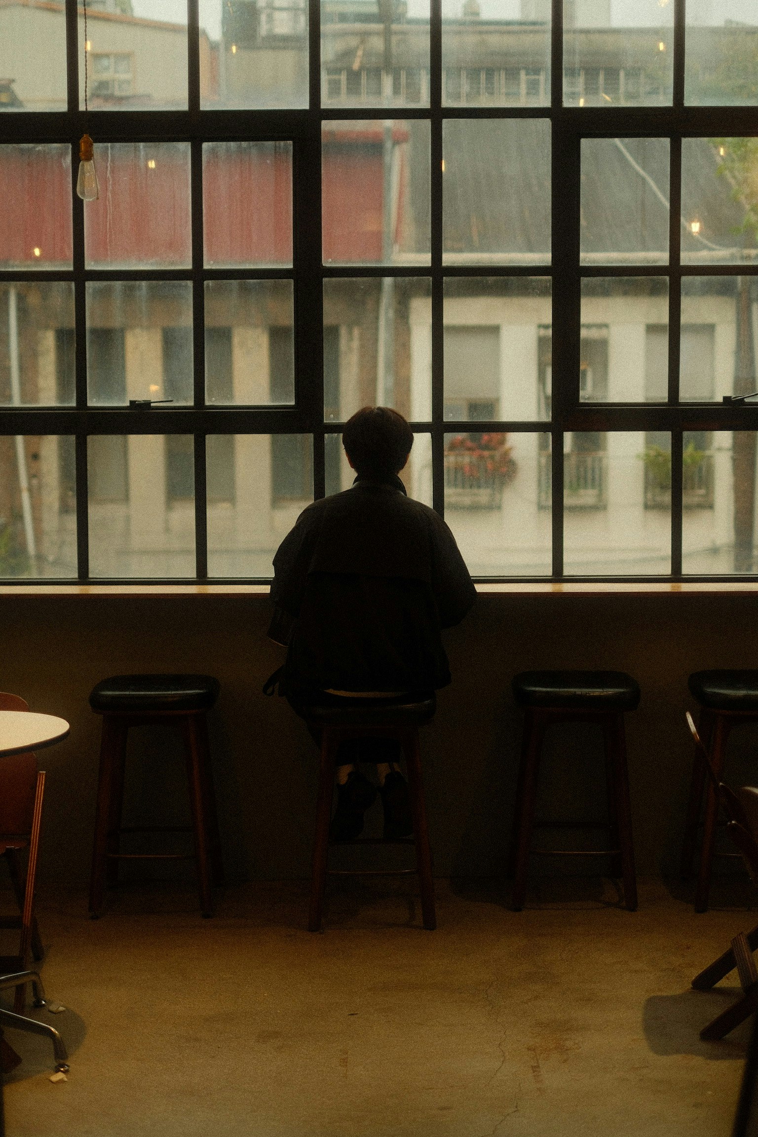 窓の外を見つめる人物のシルエット カフェの内部 スツールに座っている