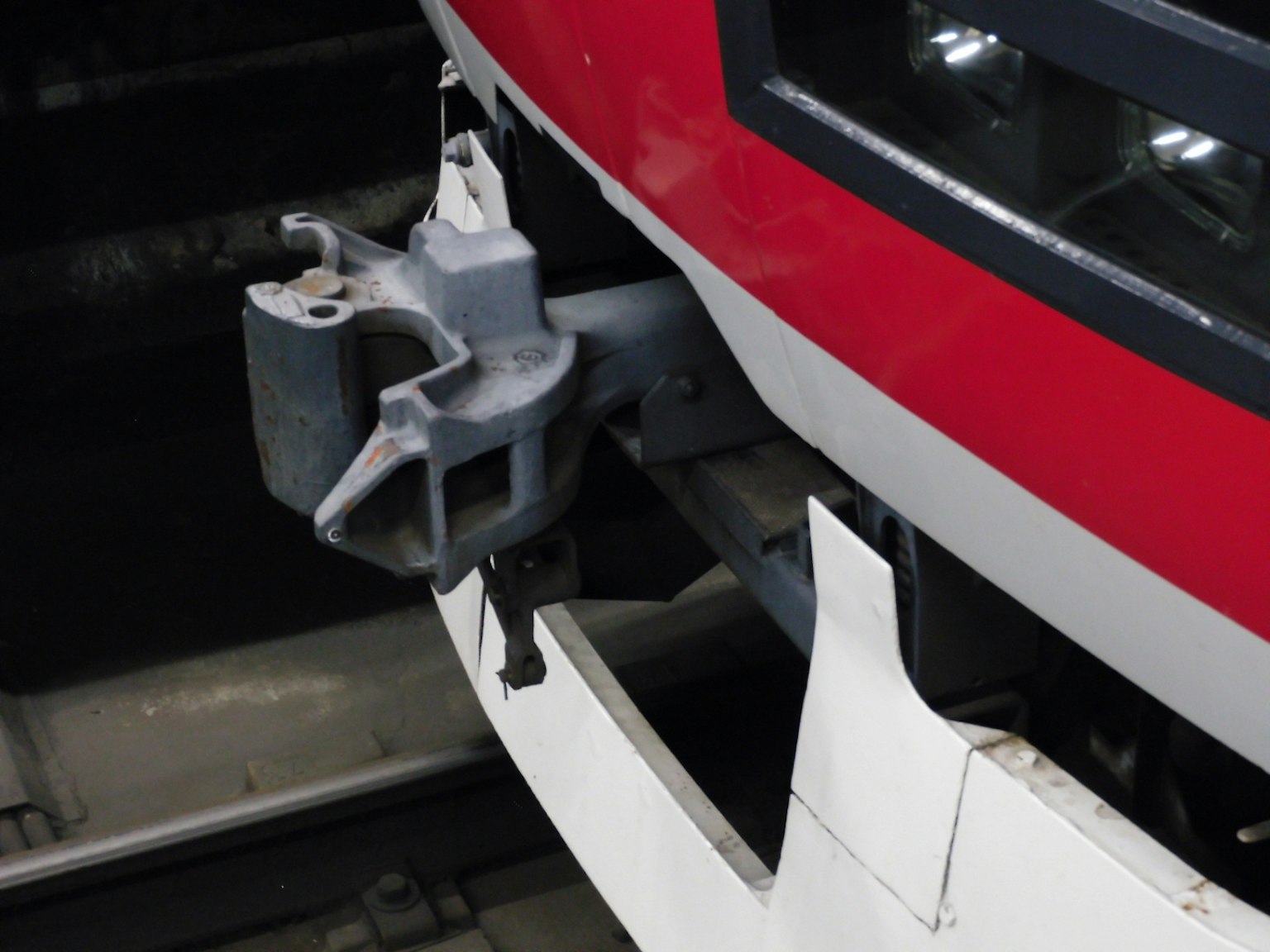 Close-up of a coupler on the front of a red train