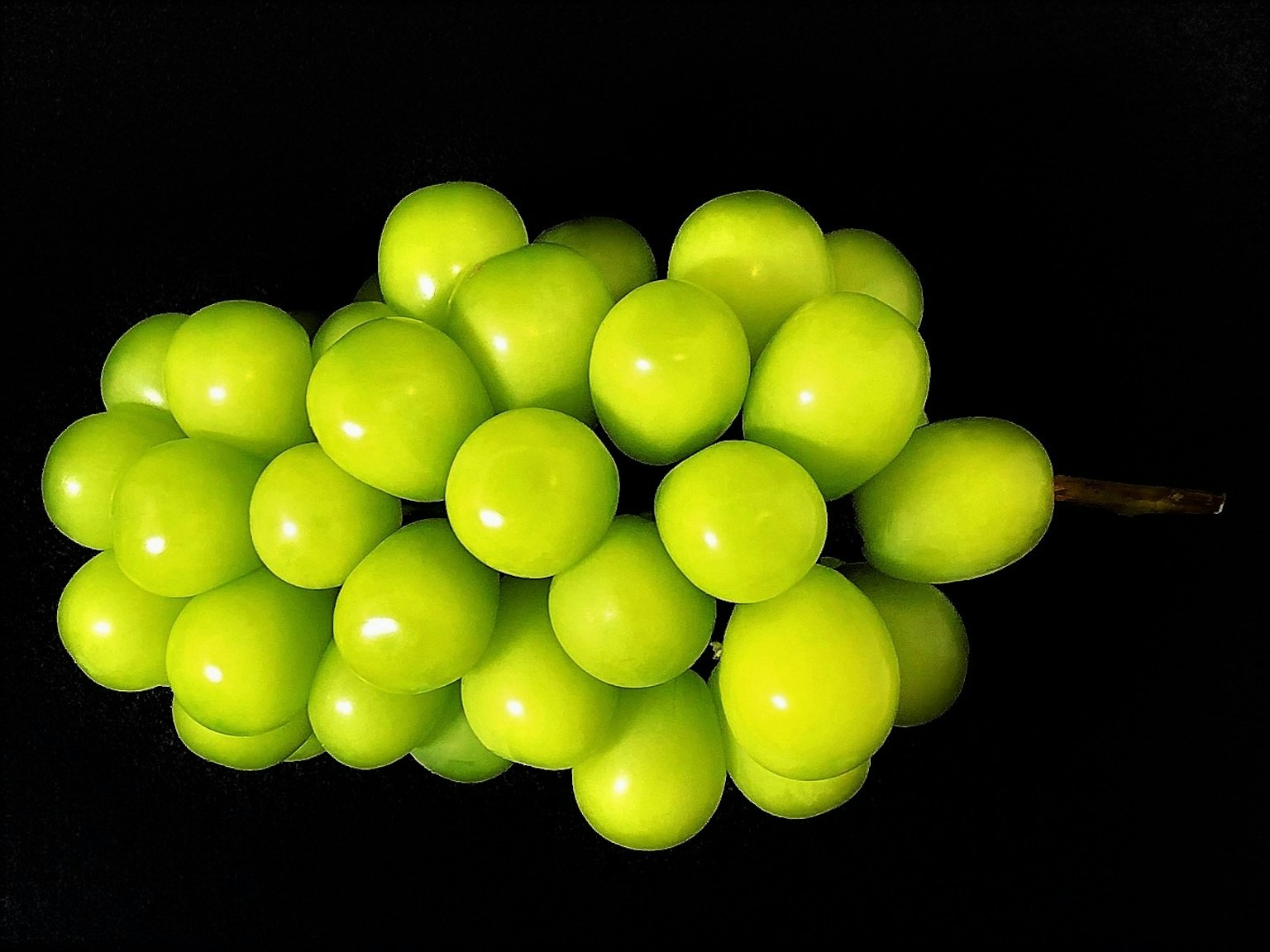Un grappolo di uva verde vibrante su uno sfondo nero