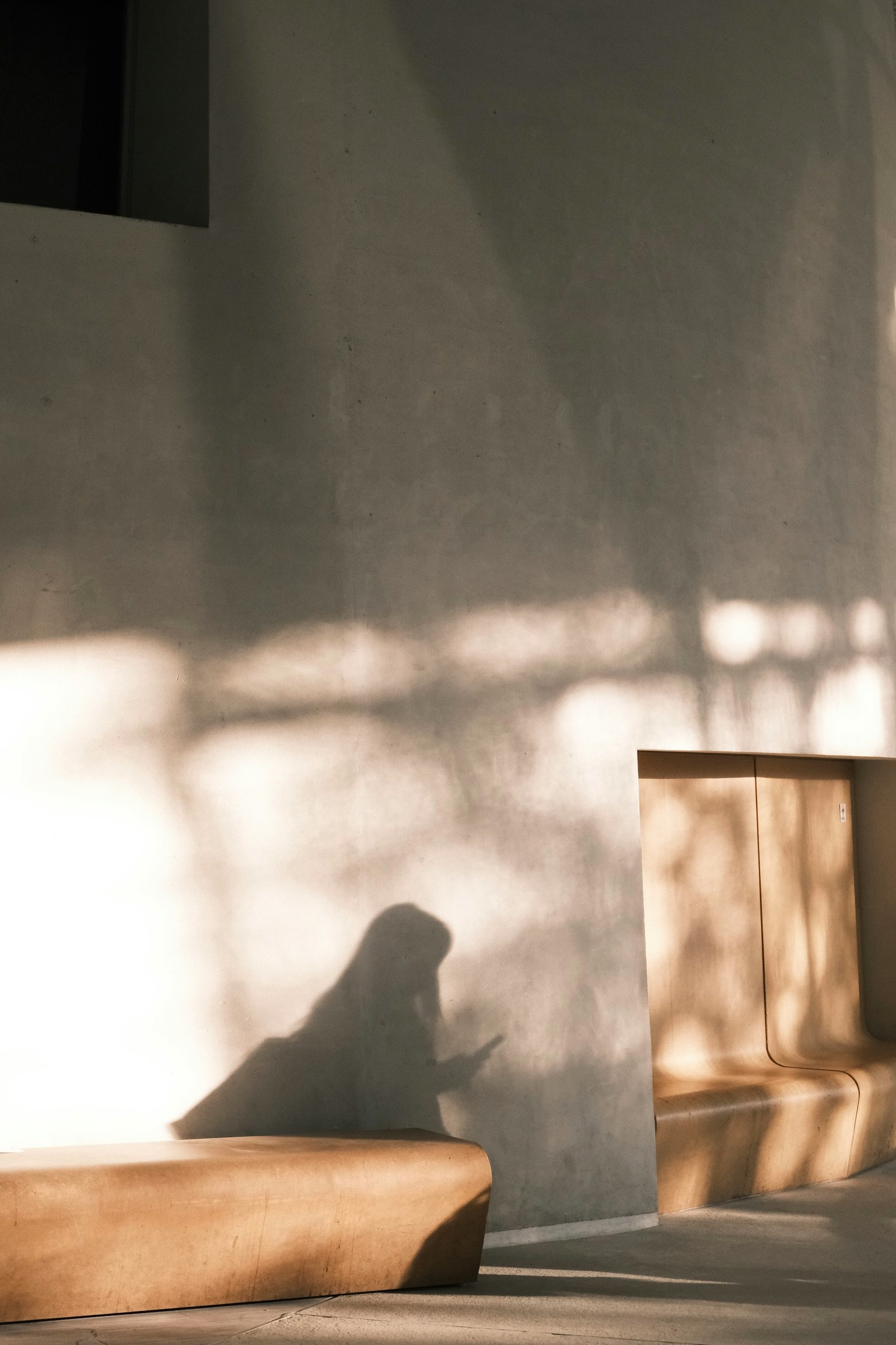 Cảnh trong nhà với bóng mềm trên tường và bóng dáng của một người đang ngồi