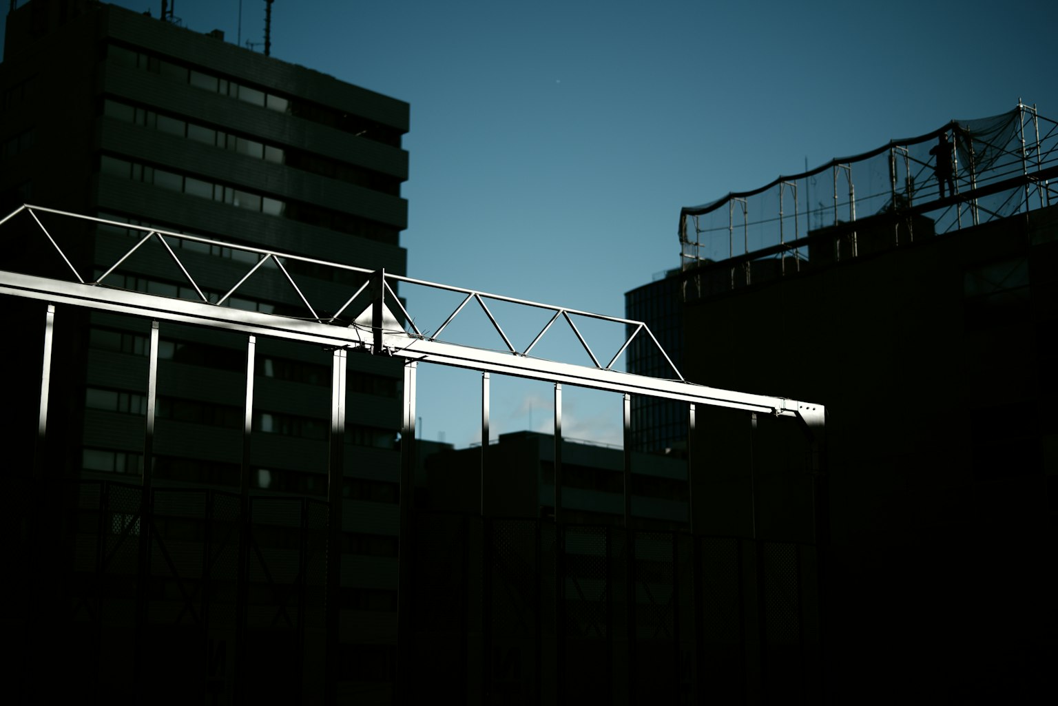 Silhouette di edifici urbani e struttura metallica contro un cielo crepuscolare